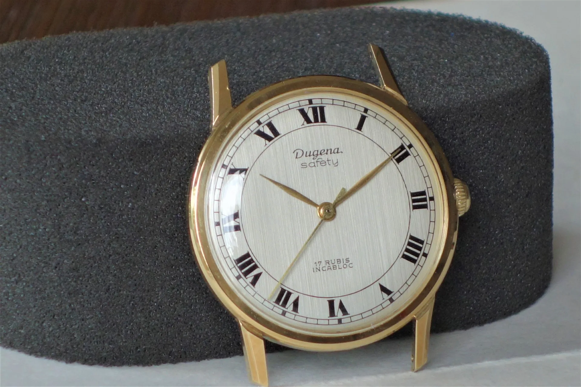 Runde Armbanduhr mit goldfarbenem Gehäuse und weißem Zifferblatt mit römischen Zahlen.