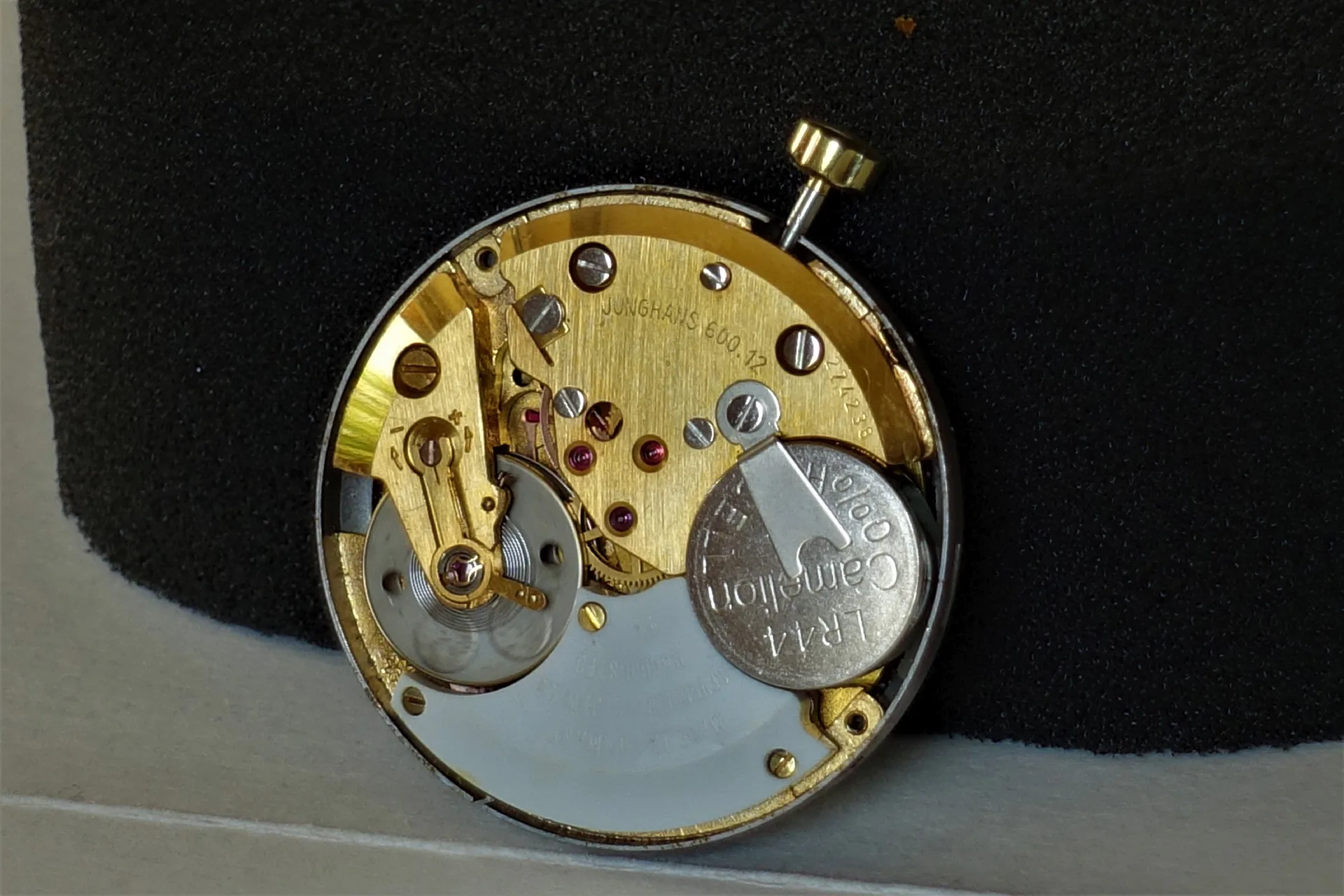 Quarzuhrwerk goldfarben Goldfarbenes Quarzuhrwerk mit sichtbarer Batterie und Aufzugswelle.