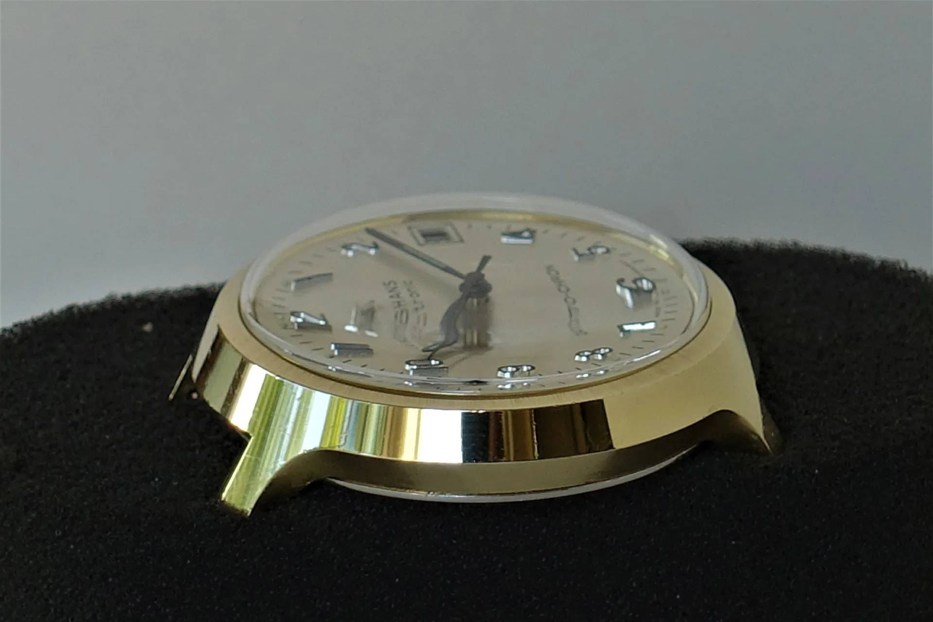 Goldfarbenes Uhrgehäuse mit Zifferblatt und Zeigern, ohne Armband.