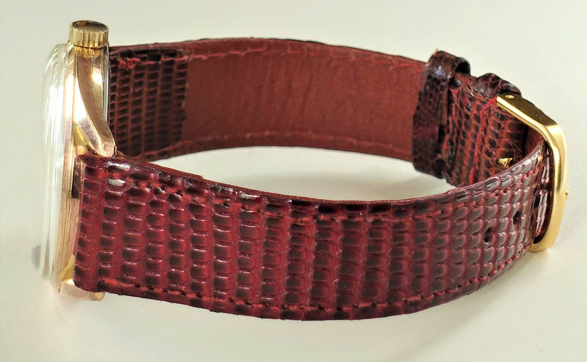 Braune Armbanduhr mit goldfarbenem Gehäuse und Schnalle.