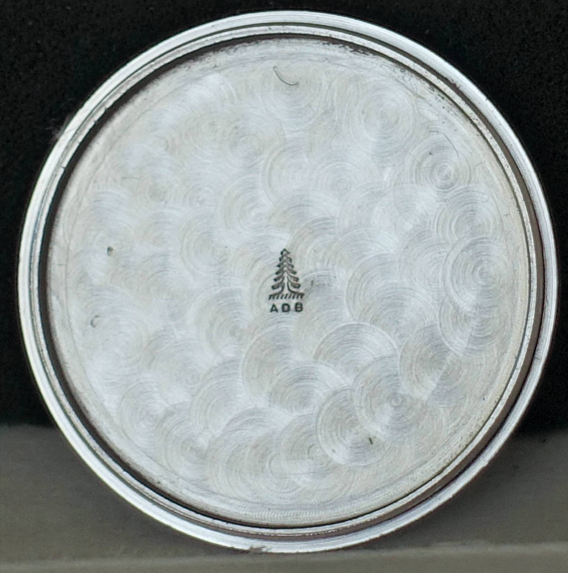 Detailaufnahme des Bodens eines Edelstahlbechers mit Wellenmuster und eingraviertem Logo.