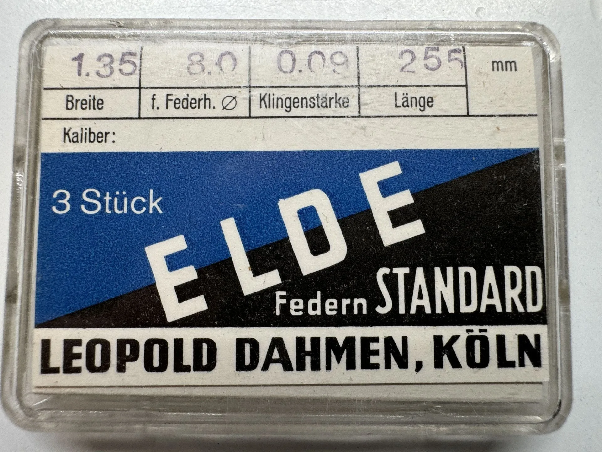 Set mit drei Uhrmacher Federn in transparenter Kunststoffbox mit Beschriftung.