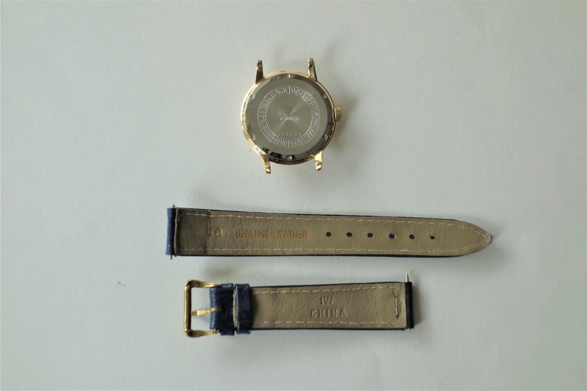 Uhrgehäuse goldfarben mit Lederarmband Goldfarbenes Uhrgehäuse mit separat liegendem zweiteiligem Lederarmband in heller Farbe.