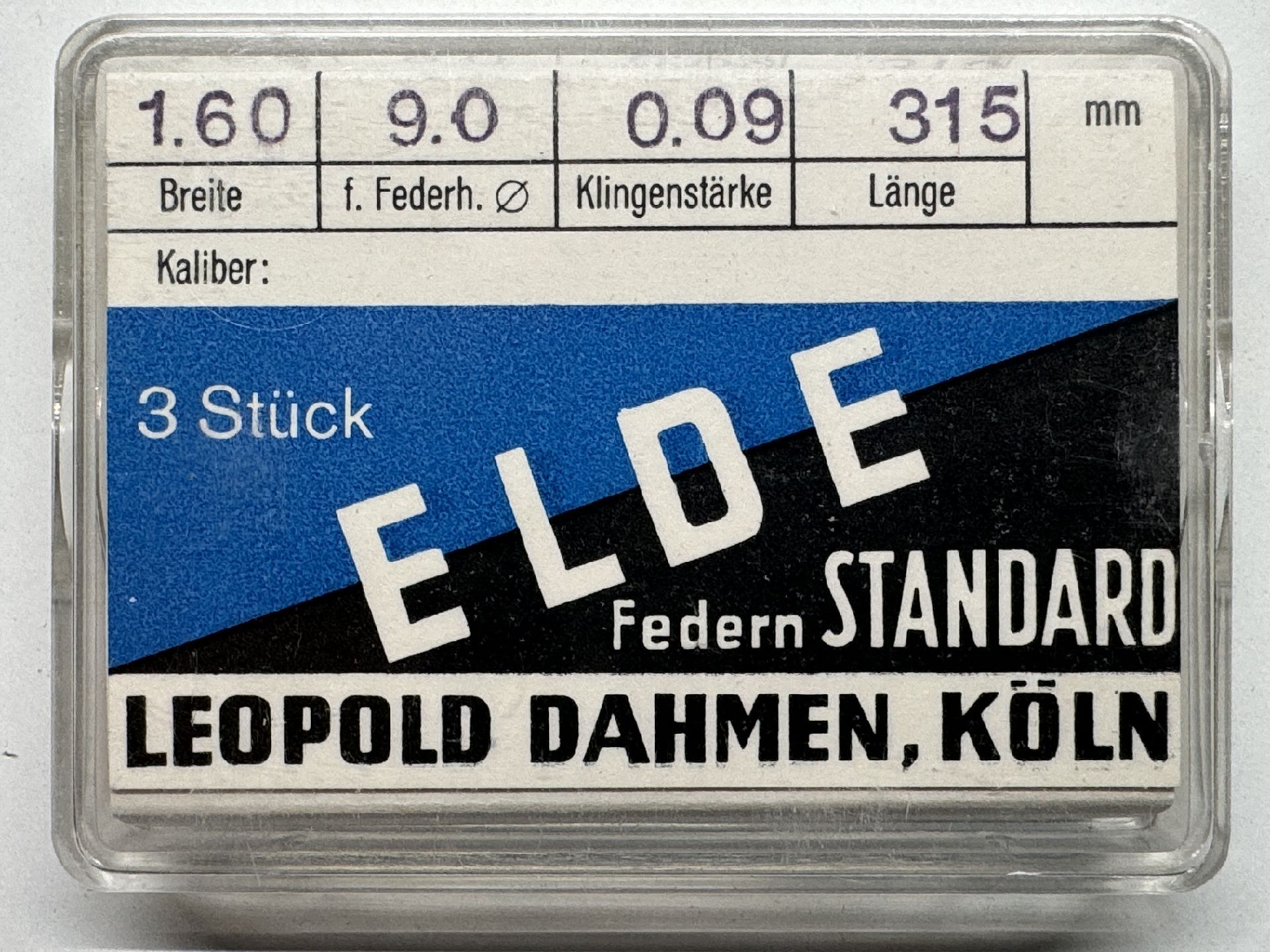 Verpackung mit drei Zugfedern für Uhren, beschriftet mit technischen Angaben und Herstellername.