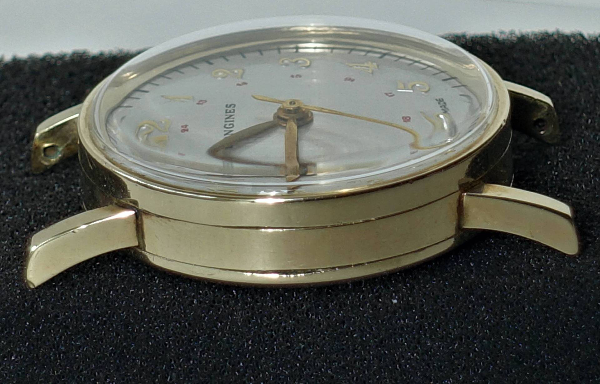 Detailaufnahme einer Vintage-Uhr mit goldfarbenem Gehäuse und weißem Ziffernblatt