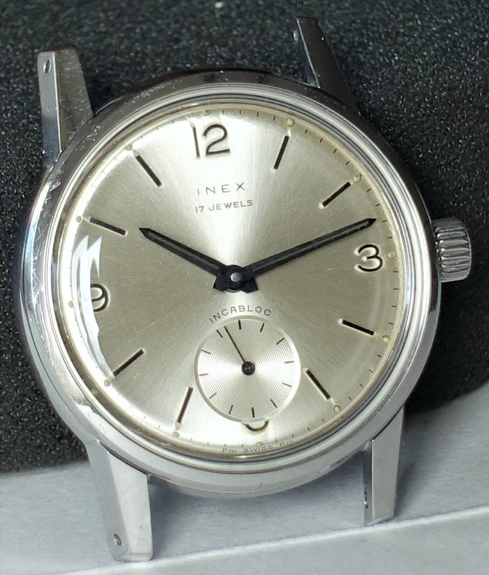 Nahaufnahme einer klassischen INEX Armbanduhr mit silbernem Zifferblatt und schwarzem Zeigerdesign.