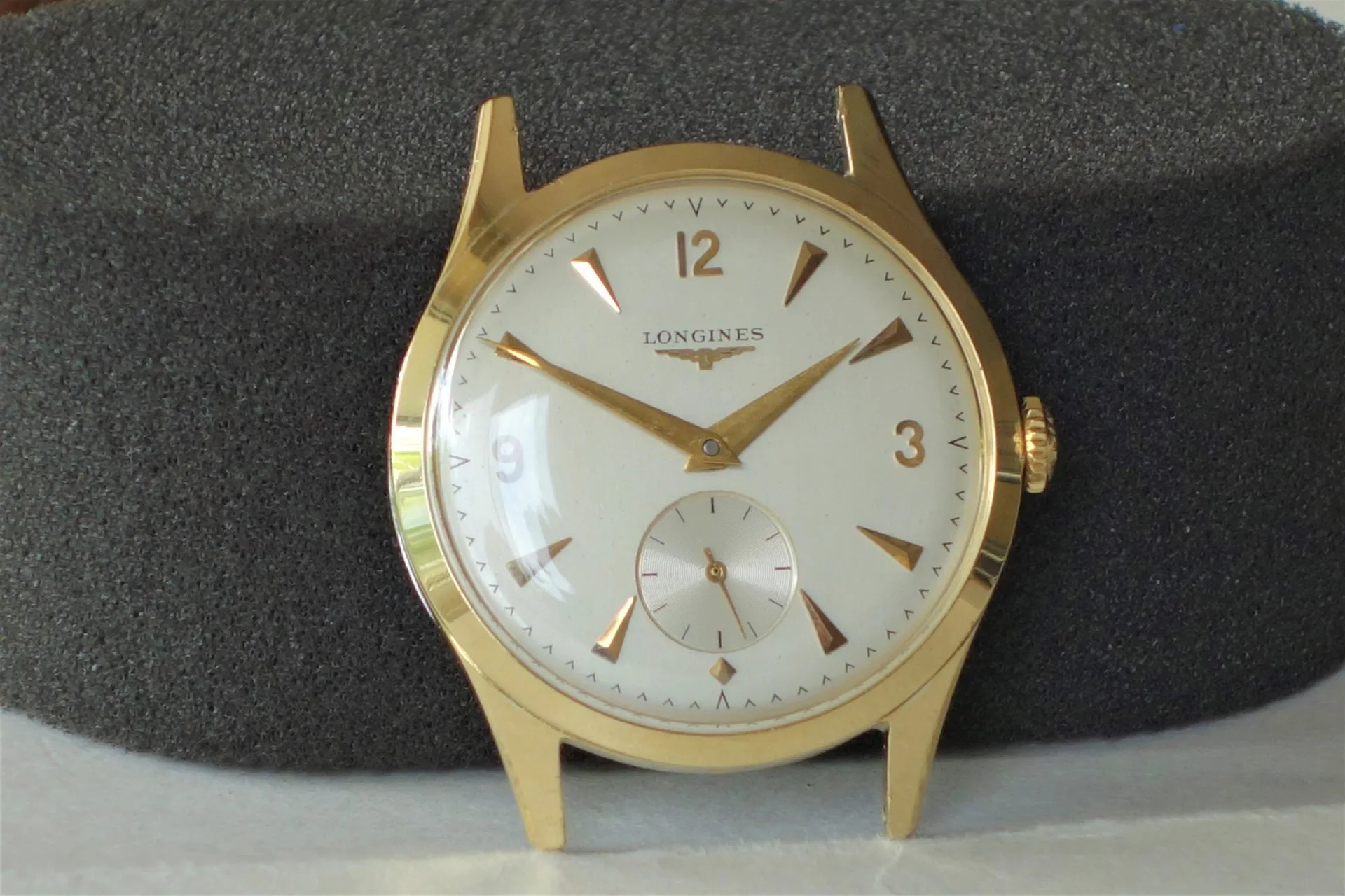 Runde Armbanduhr mit goldfarbenem Gehäuse und weißem Zifferblatt.