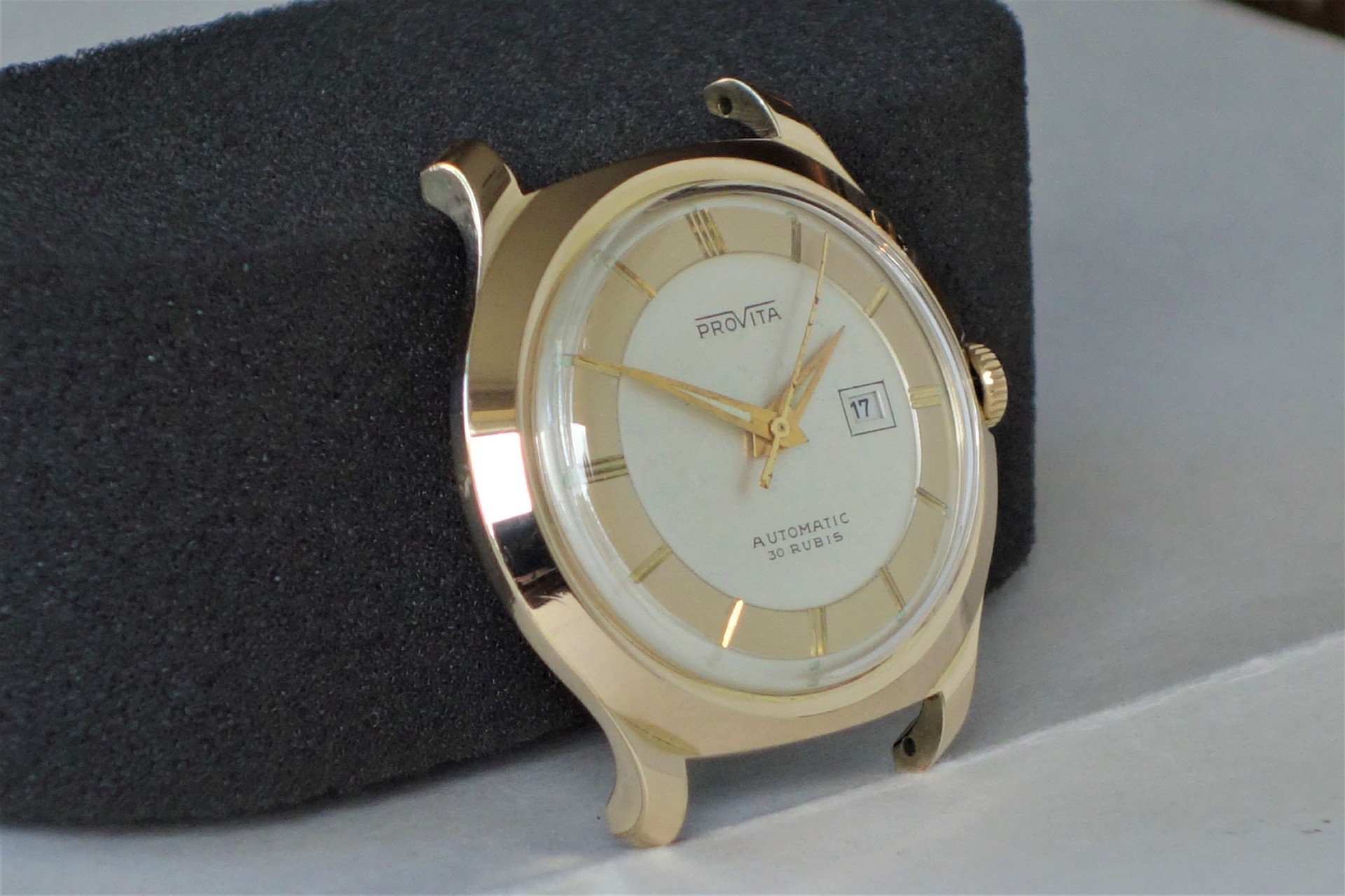 Runde Armbanduhr mit goldfarbenem Gehäuse und Zeigern, hellem Zifferblatt und Datumsanzeige.