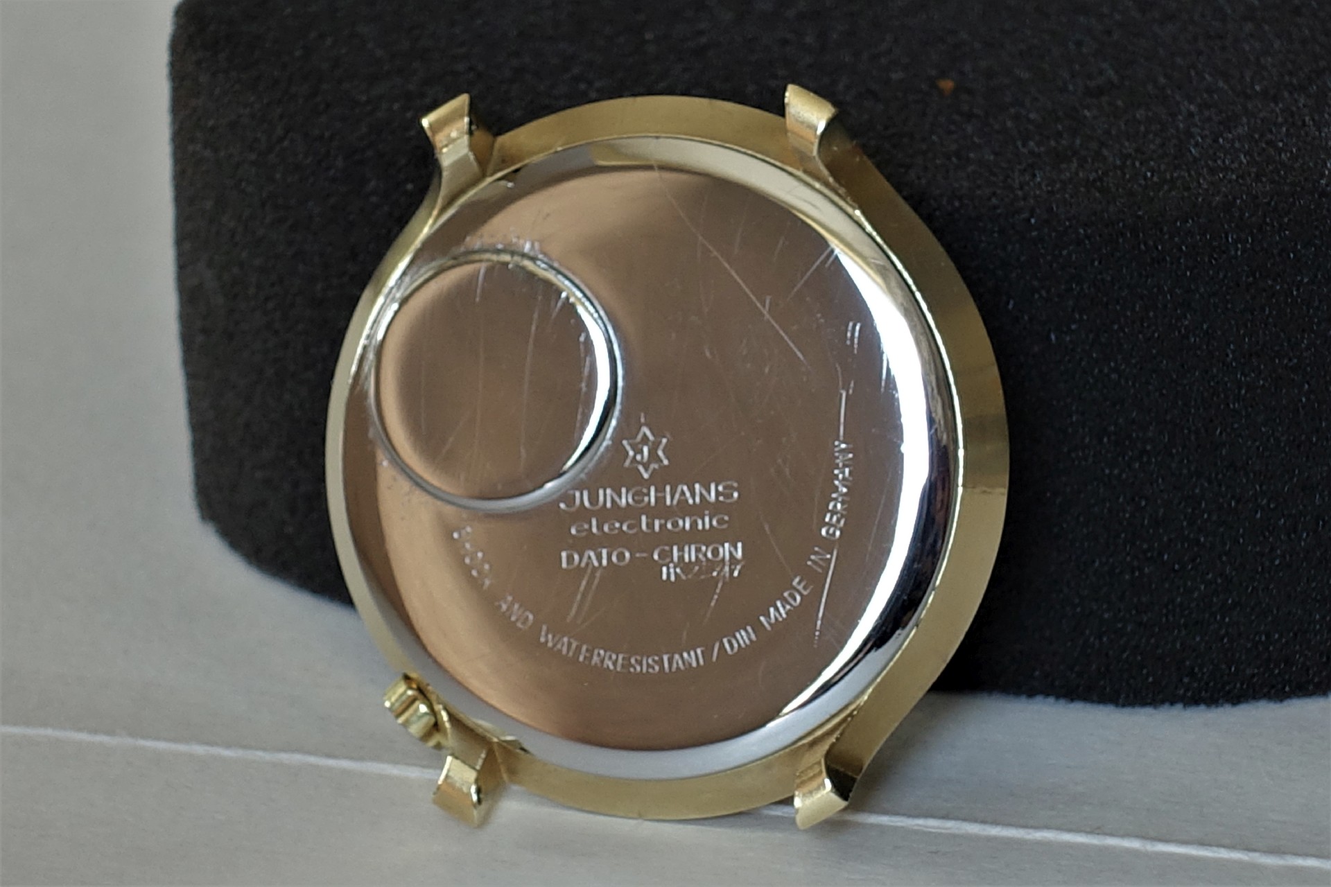 Silberfarbene Gehäuserückseite einer Uhr mit Gravur und Batterieabdeckung.