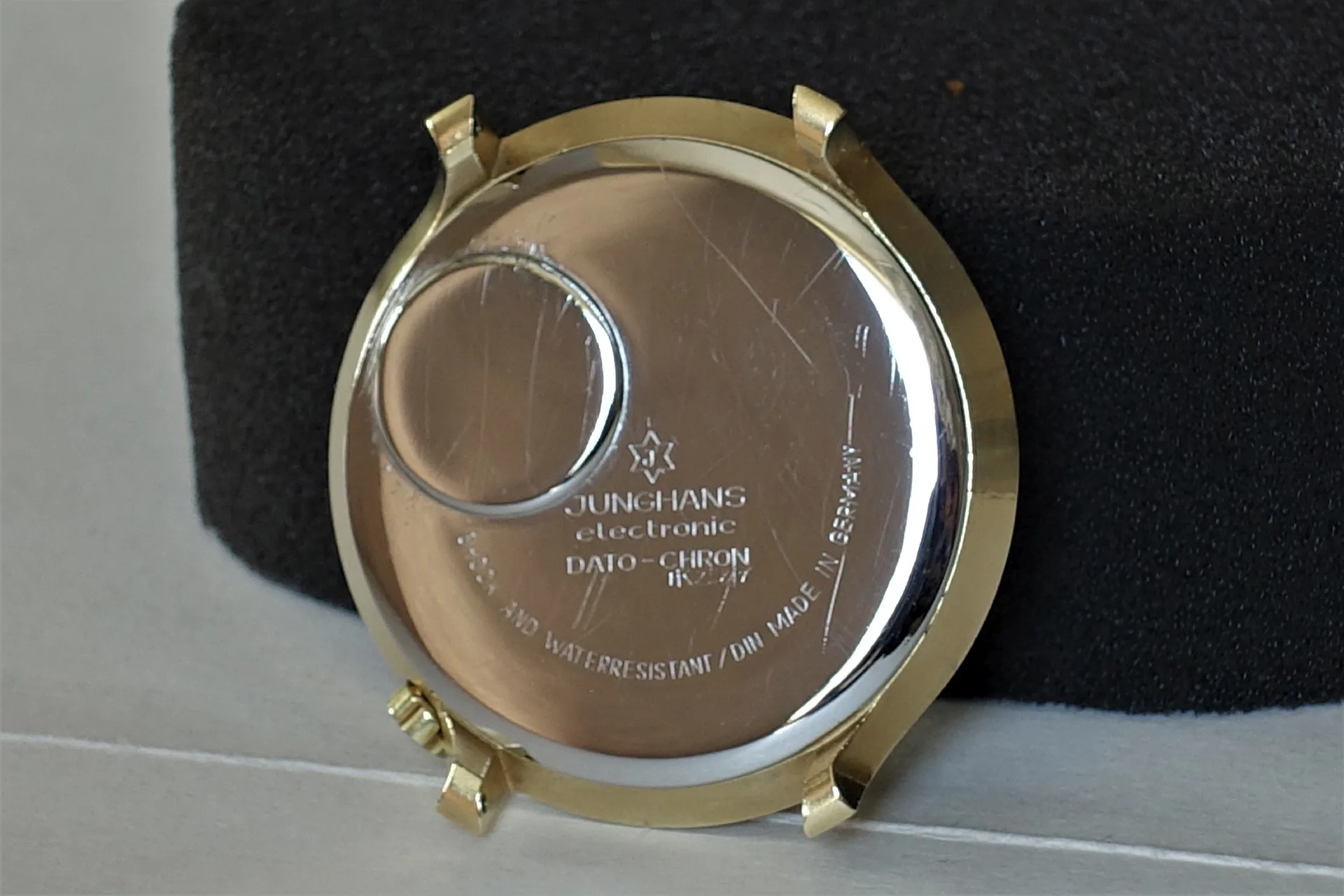 Silberfarbene Gehäuserückseite einer Uhr mit Gravur und Batterieabdeckung.