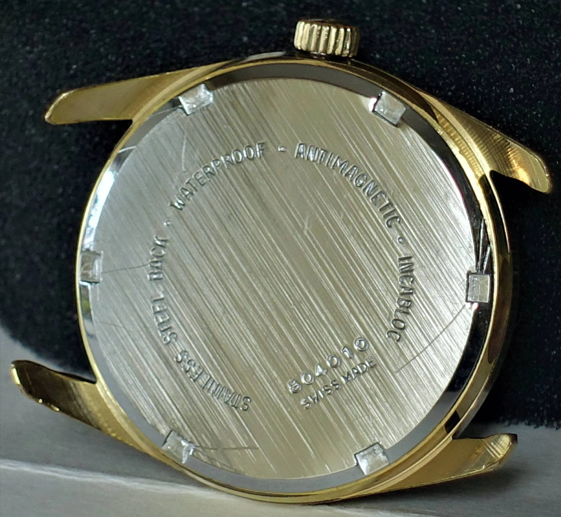 Gehäuse goldfarben Rundes Uhrengehäuse in goldfarbener Optik mit silberfarbener Rückseite und sichtbarer Krone.