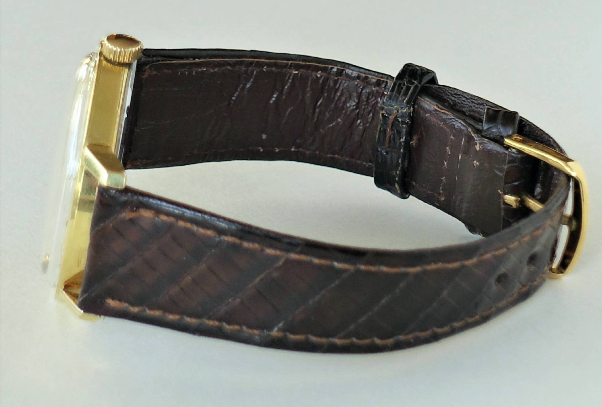 Armbanduhr mit braunem Armband und goldfarbenem Gehäuse.