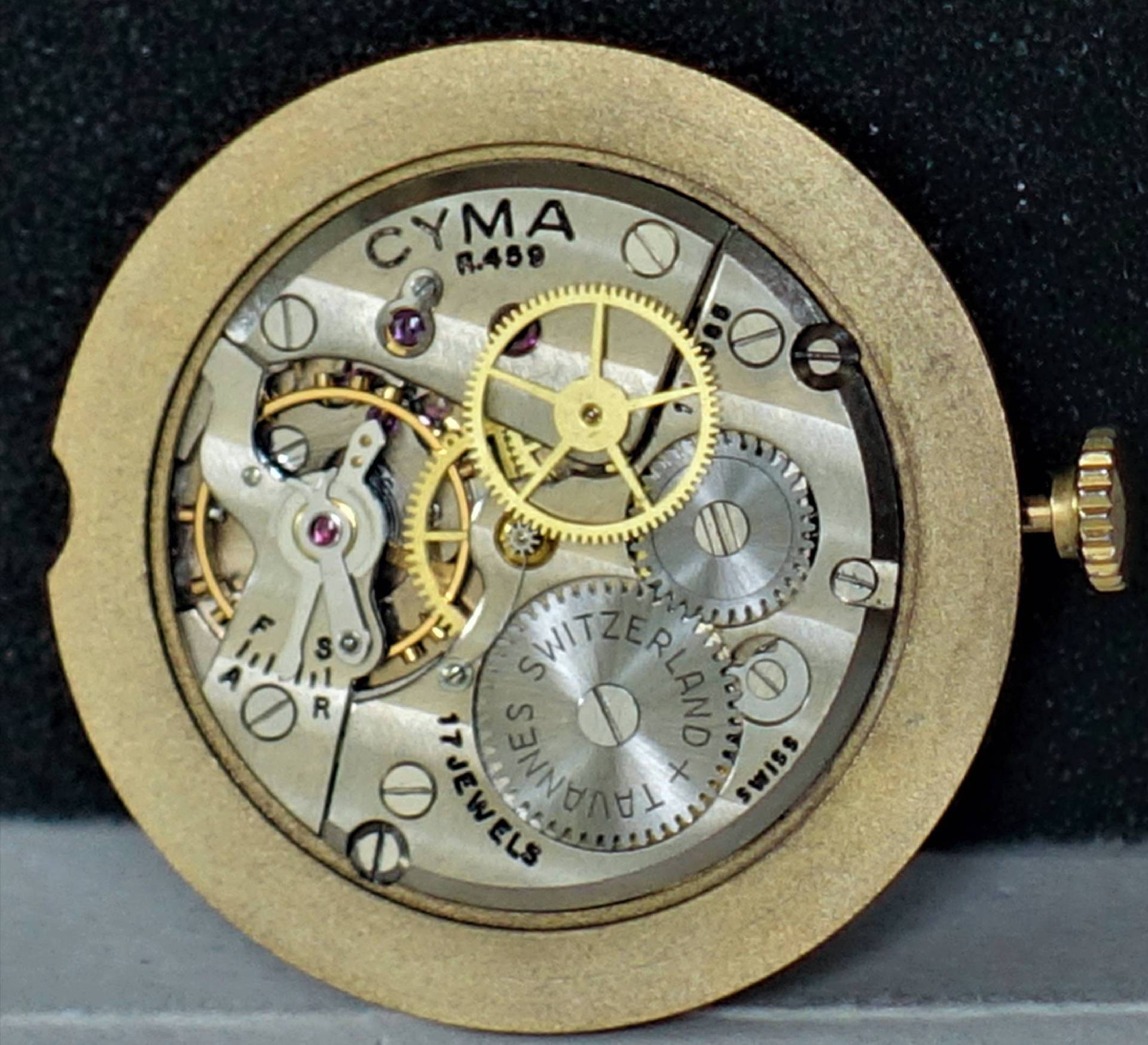 Mechanisches Uhrwerk CYMA R459 mit sichtbaren Zahnrädern und goldfarbener Krone.
