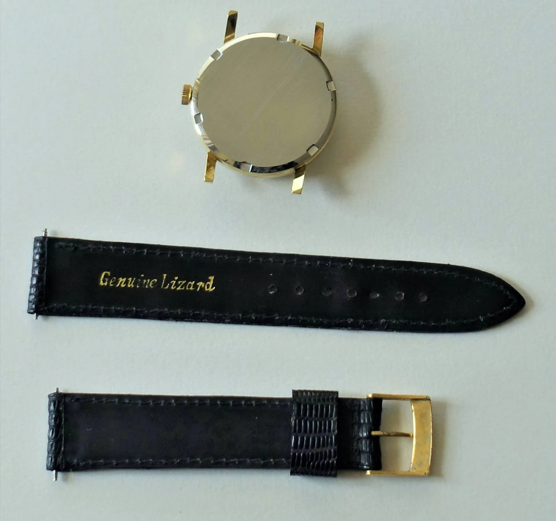 Rundes Uhrgehäuse in goldfarben mit schwarzem Lederarmband und goldfarbener Dornschließe.