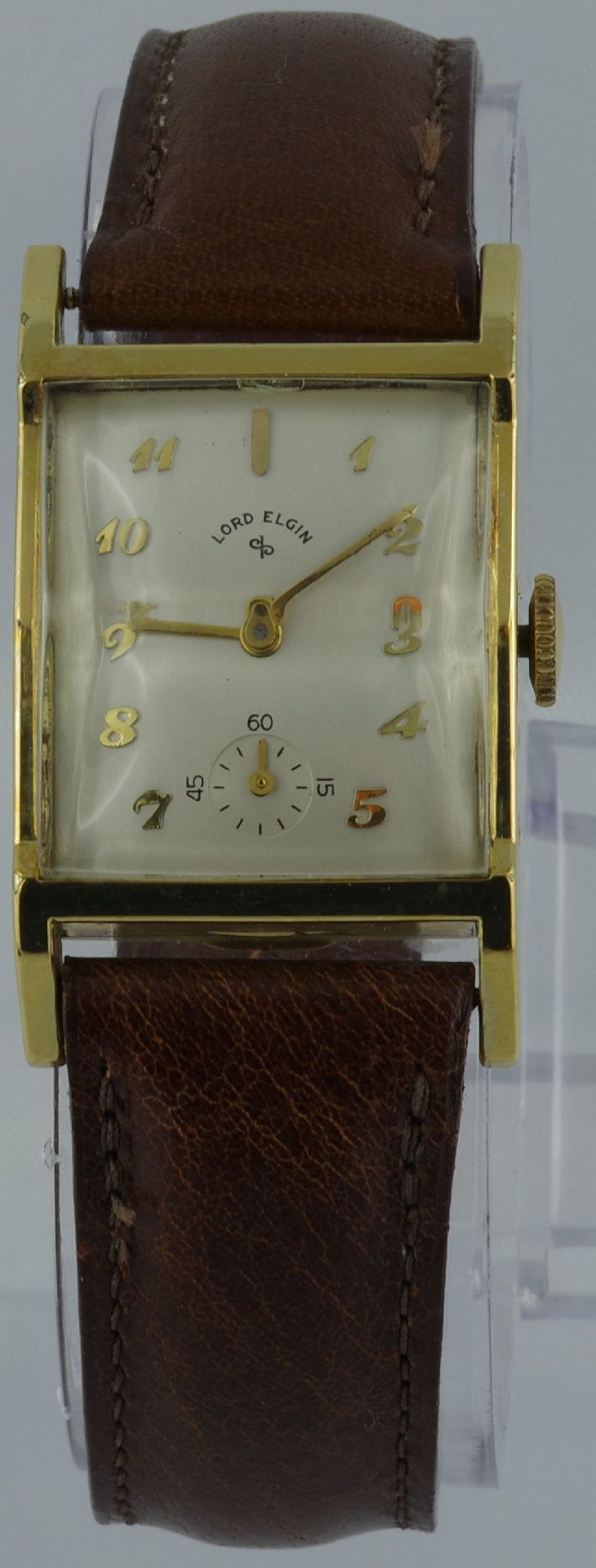 Rechteckige Armbanduhr mit braunem Armband und hellem Zifferblatt.