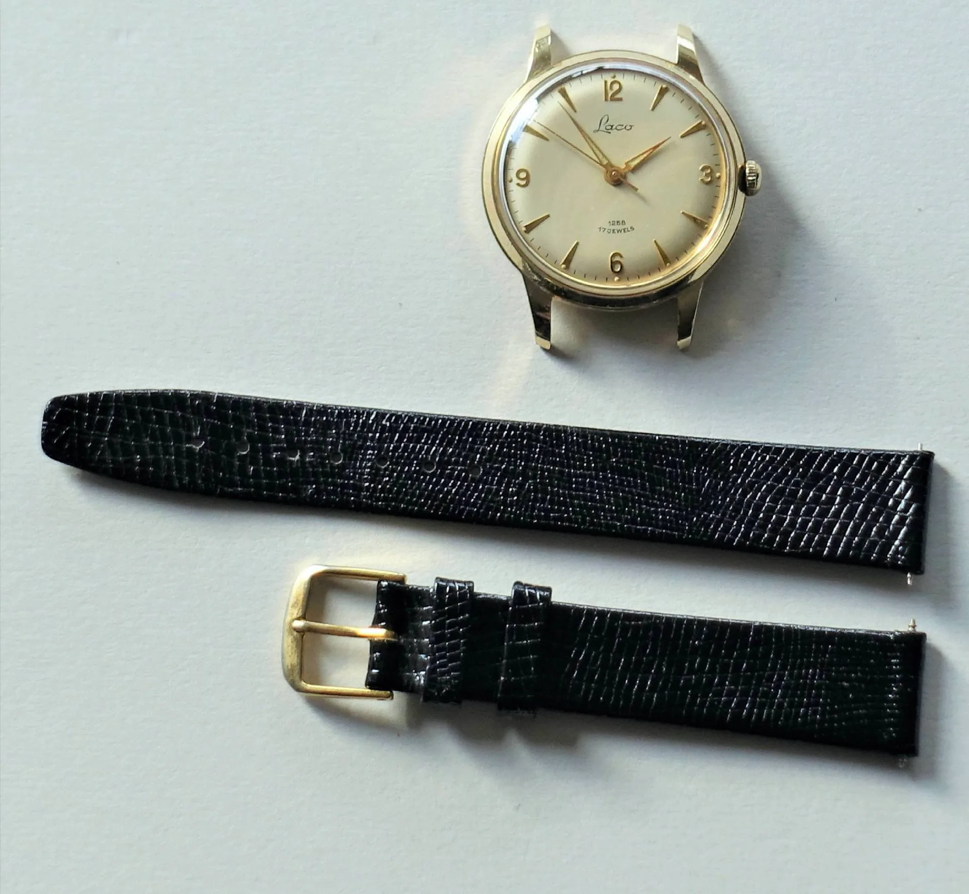 Armbanduhr goldfarben mit Lederarmband Goldfarbene Armbanduhr mit hellem Zifferblatt und schwarzem Lederarmband in zwei Teilen.