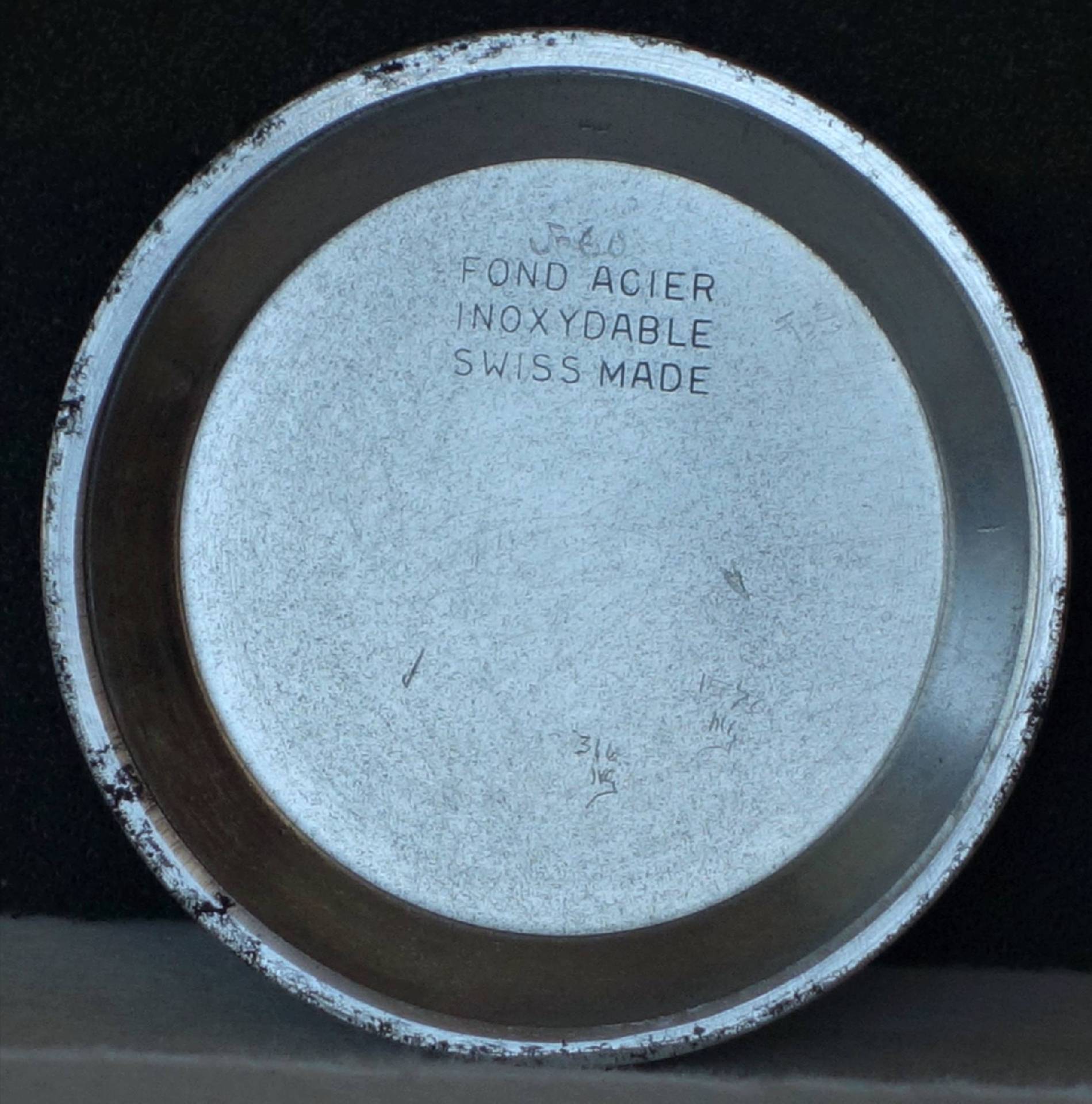 Runder silberfarbener Uhrenboden mit Gravur auf der Innenseite.