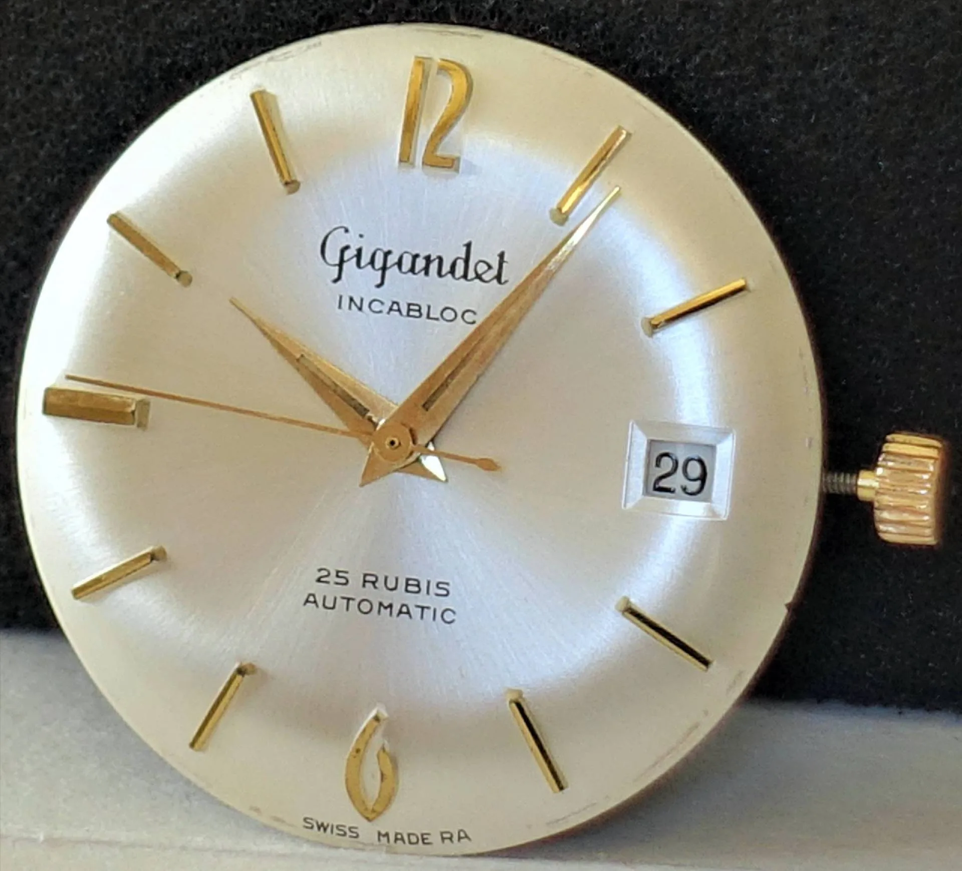 Silbernes Zifferblatt goldene Details Rundes silberfarbenes Uhrwerk mit goldfarbenen Zeigern, Indizes und Krone, Datumsanzeige bei drei Uhr, Marke "Gigandet".