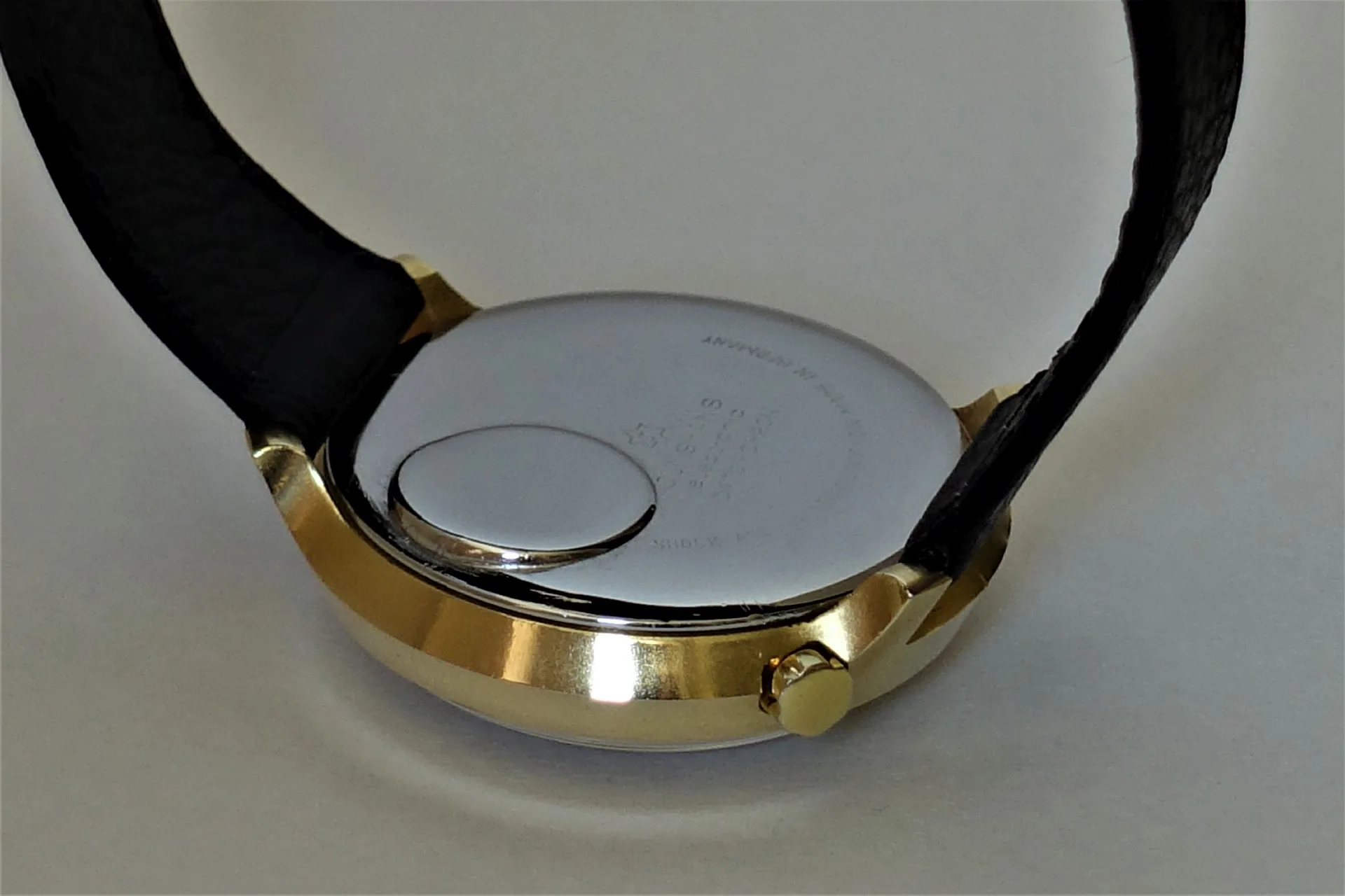 Uhrenboden silberfarben Silberfarbener Uhrenboden mit goldfarbener Gehäusekante und schwarzem Armband.