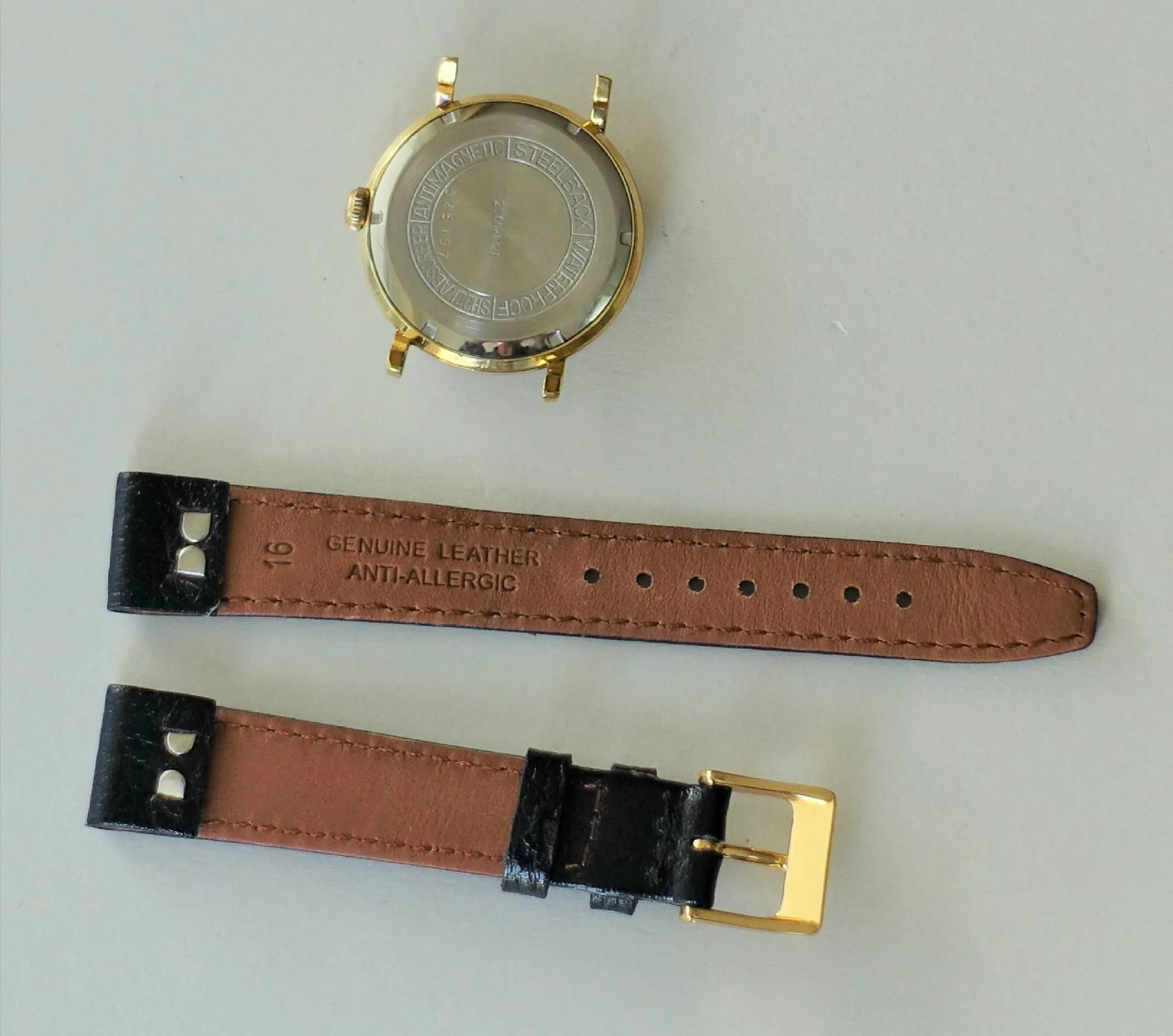 Uhrgehäuse goldfarben und Lederarmband Rundes Uhrgehäuse in goldfarbener Optik mit separatem braun-schwarzem Lederarmband und goldfarbener Schließe.