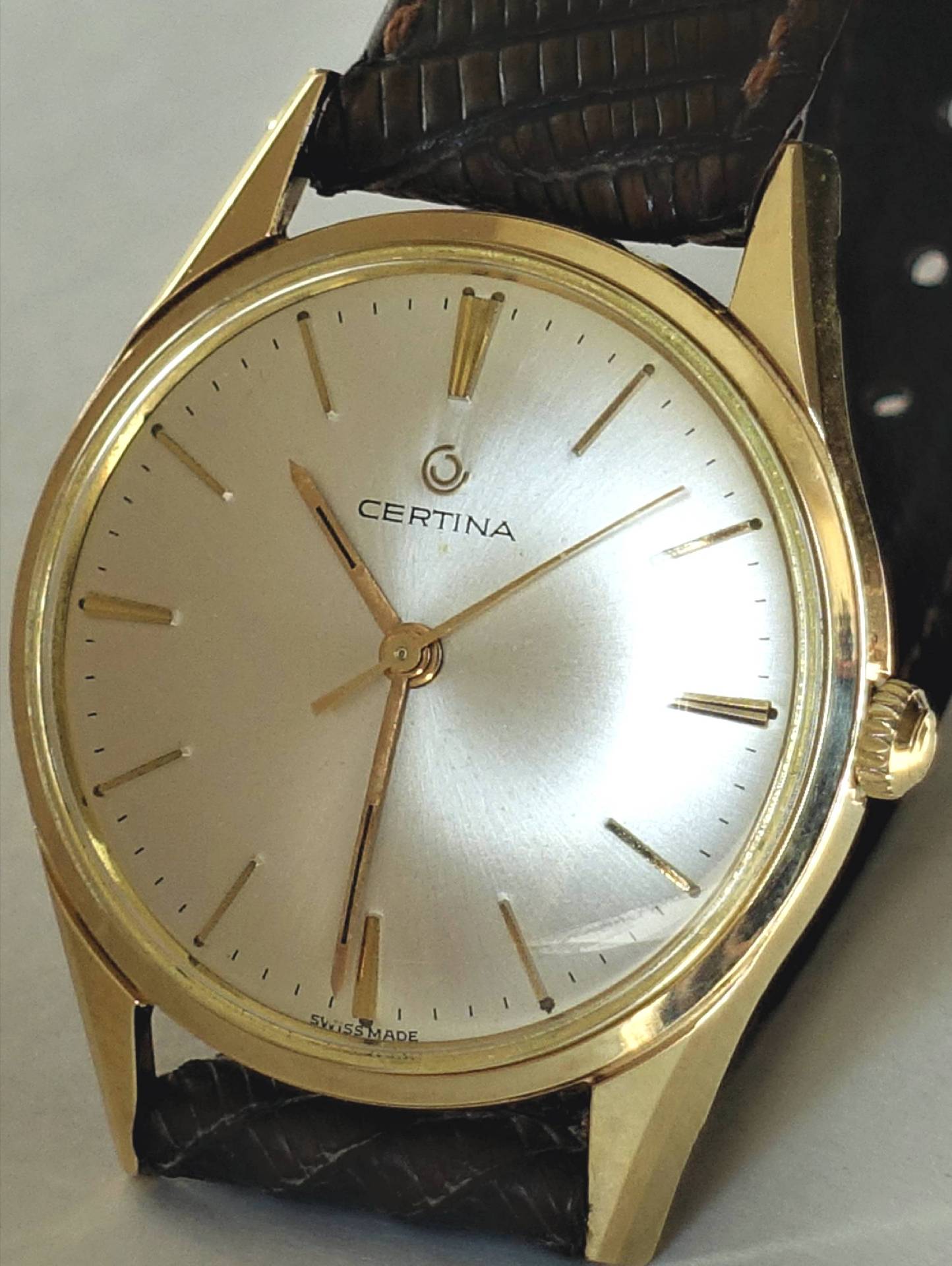 Goldfarbene Certina Armbanduhr mit silbernem Zifferblatt und braunem Armband.