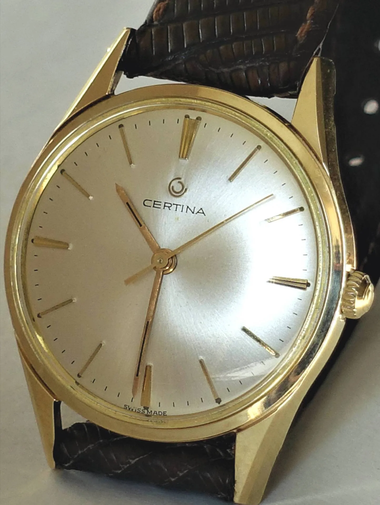 Goldfarbene Certina Armbanduhr mit silbernem Zifferblatt und braunem Armband.