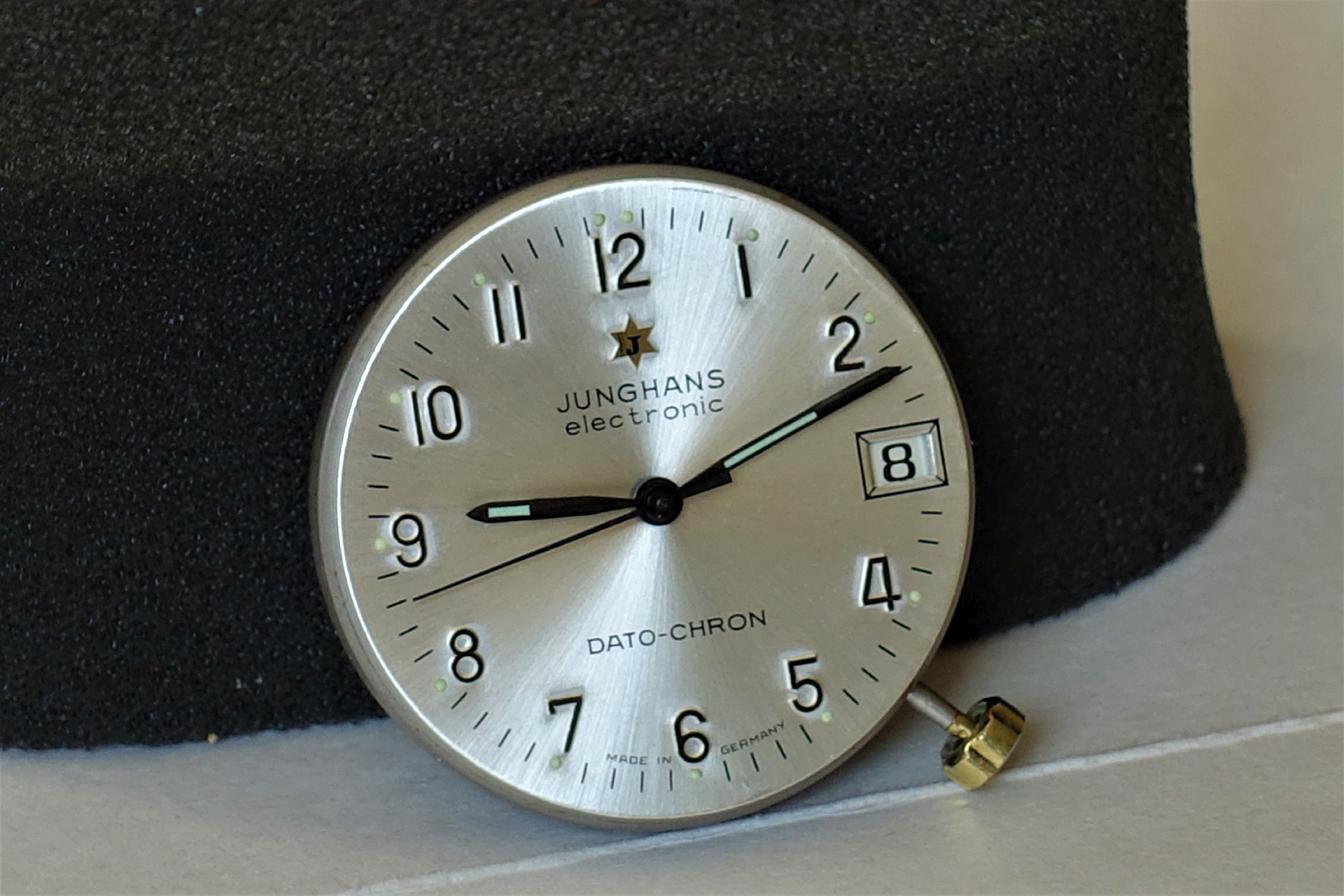 Silberfarbenes Zifferblatt einer Junghans Dato-Chron Uhr mit schwarzen Zeigern und Datumsanzeige.