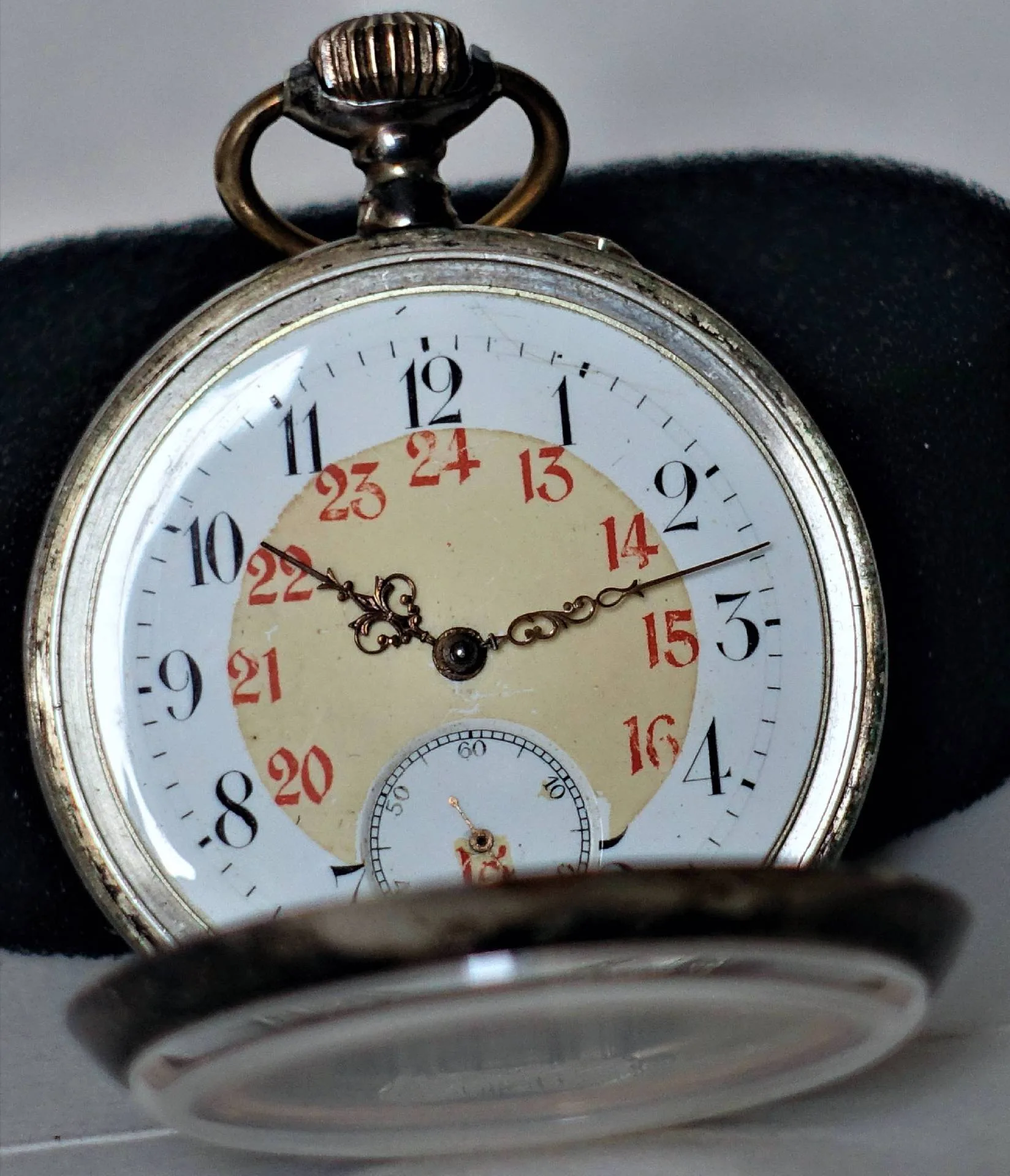 Silberfarbene Taschenuhr mit weißem Zifferblatt, schwarzen und roten Zahlen sowie verzierten Zeigern.