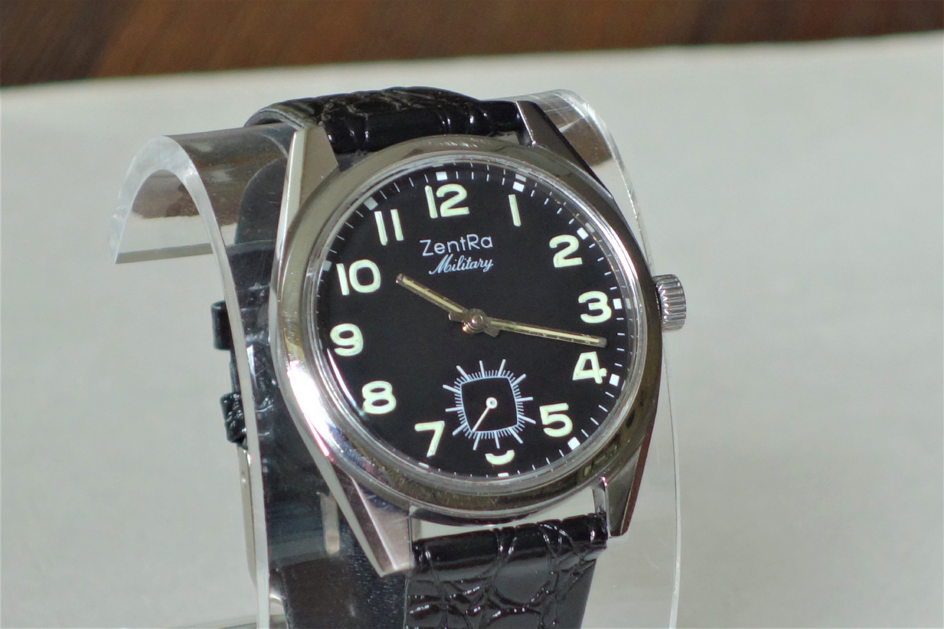 Schwarze Armbanduhr mit Leuchtziffern und schwarzem Armband.