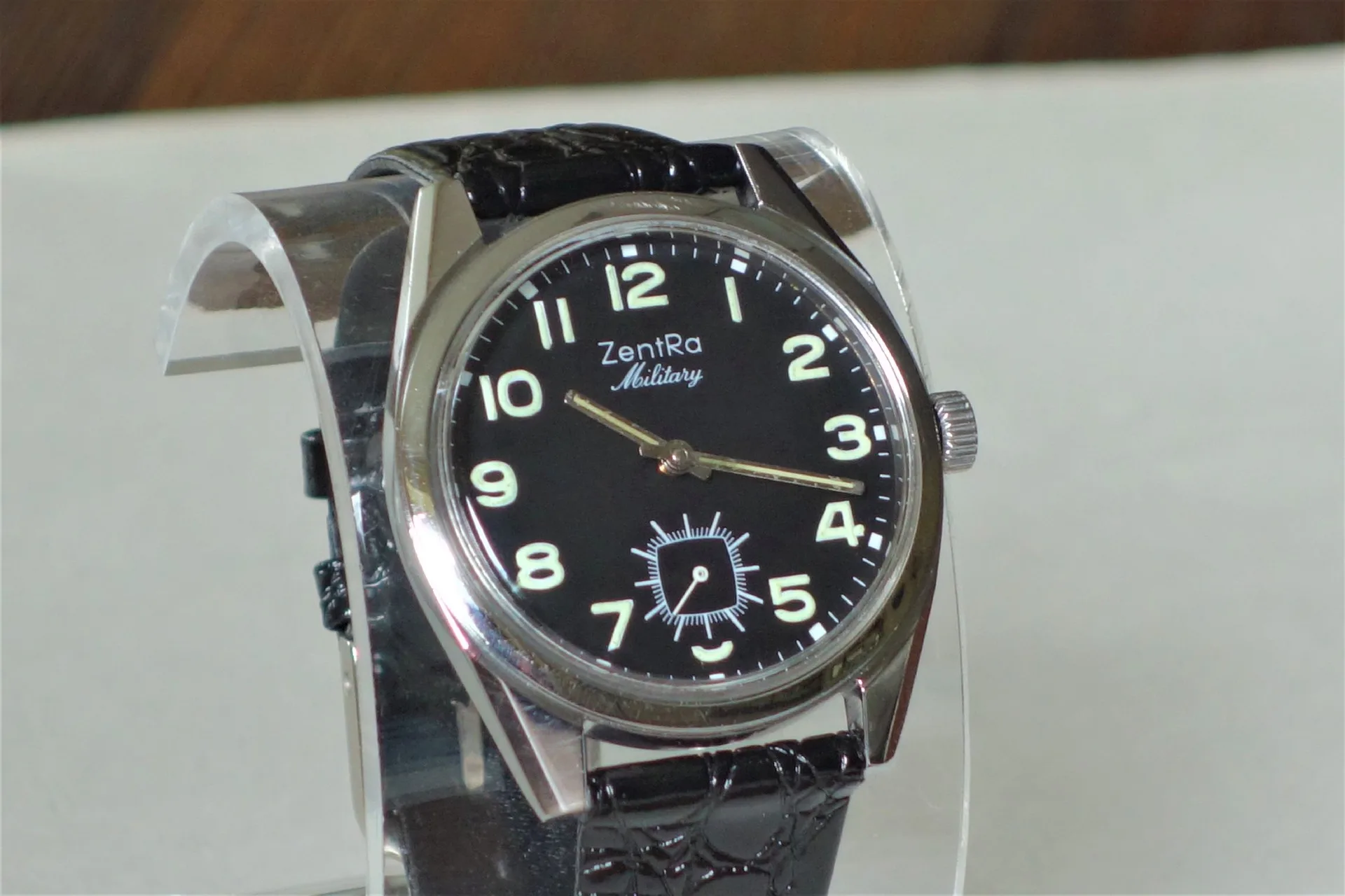 Schwarze Armbanduhr mit Leuchtziffern und schwarzem Armband.