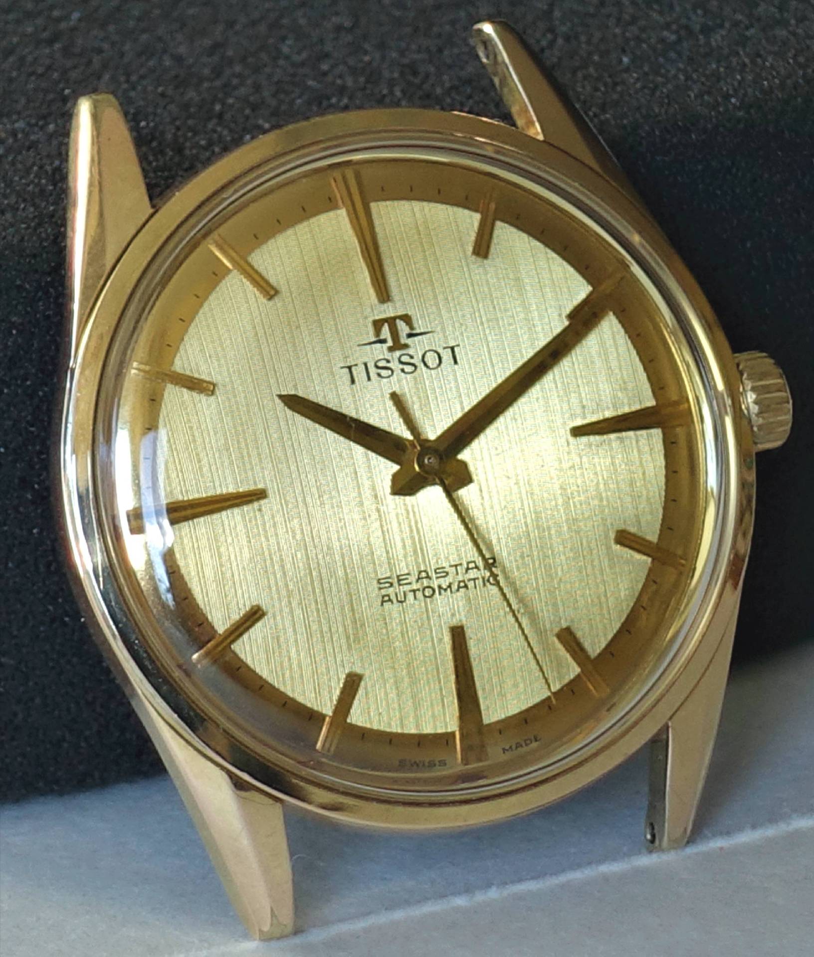 Goldfarbene Armbanduhr mit hellem Zifferblatt und drei Zeigern, Aufschrift "Tissot Seastar Automatic".