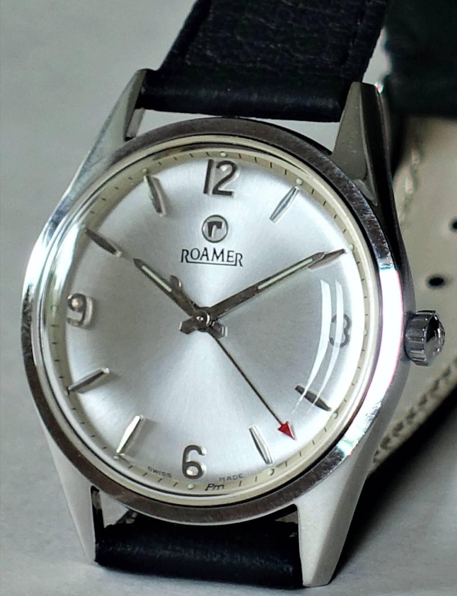 Silberfarbene Armbanduhr mit schwarzem Armband und schlichtem Zifferblatt der Marke Roamer.