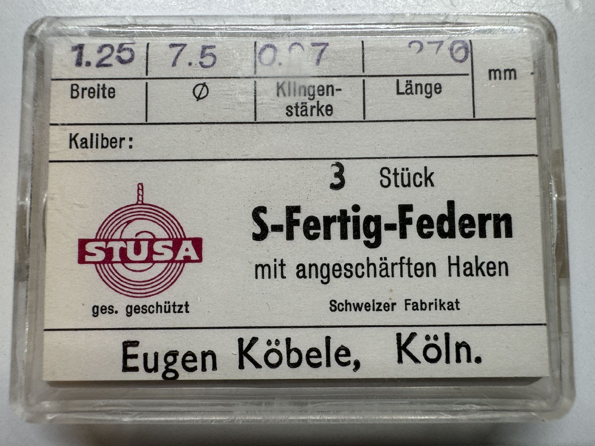 Set mit drei S-Fertig-Federn für Uhren mit angeschärften Haken in transparenter Kunststoffbox.