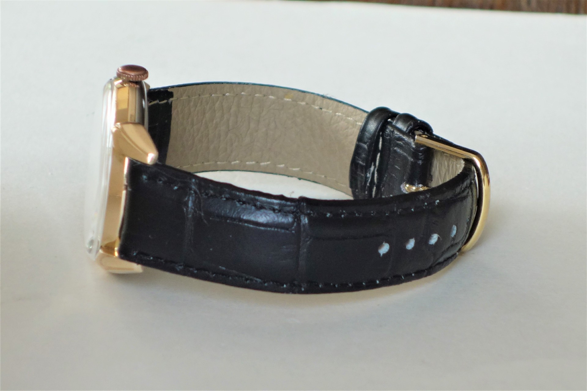 Armbanduhr mit schwarzem Armband und goldfarbenem Gehäuse.