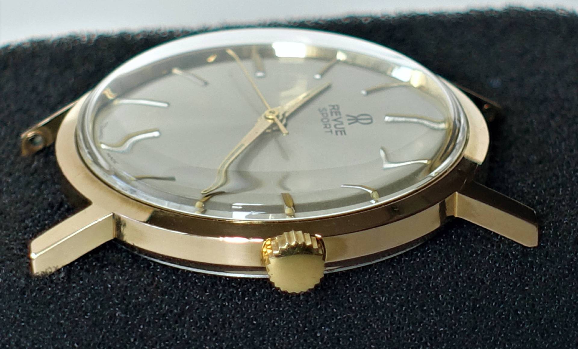 Flache goldfarbene Armbanduhr mit silberfarbenem Zifferblatt und goldenen Zeigern, Aufschrift "Revue Sport".