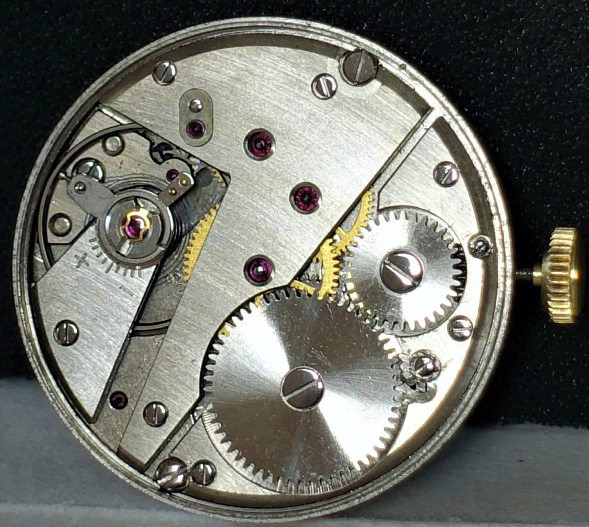 Mechanisches Uhrwerk silberfarben Silberfarbenes mechanisches Uhrwerk mit sichtbaren Zahnrädern und goldfarbener Krone.