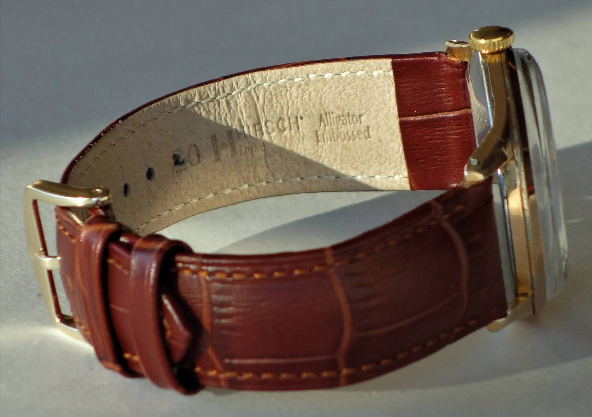 Braunes Uhrenarmband mit Prägung und goldfarbener Dornschließe.