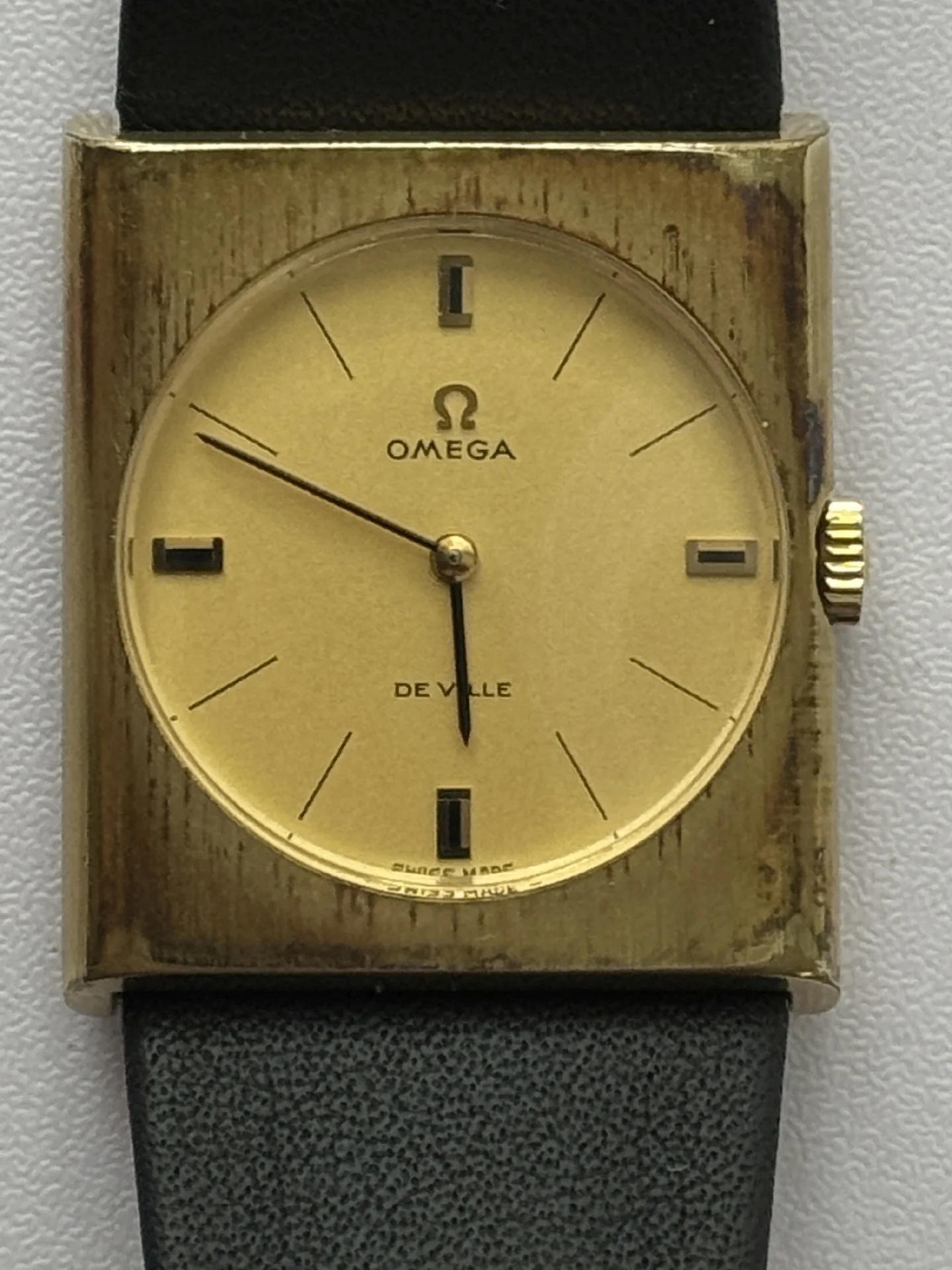 Omega De Ville Armbanduhr Rechteckige Armbanduhr mit goldfarbenem Zifferblatt und schwarzem Lederarmband, Modell Omega De Ville.