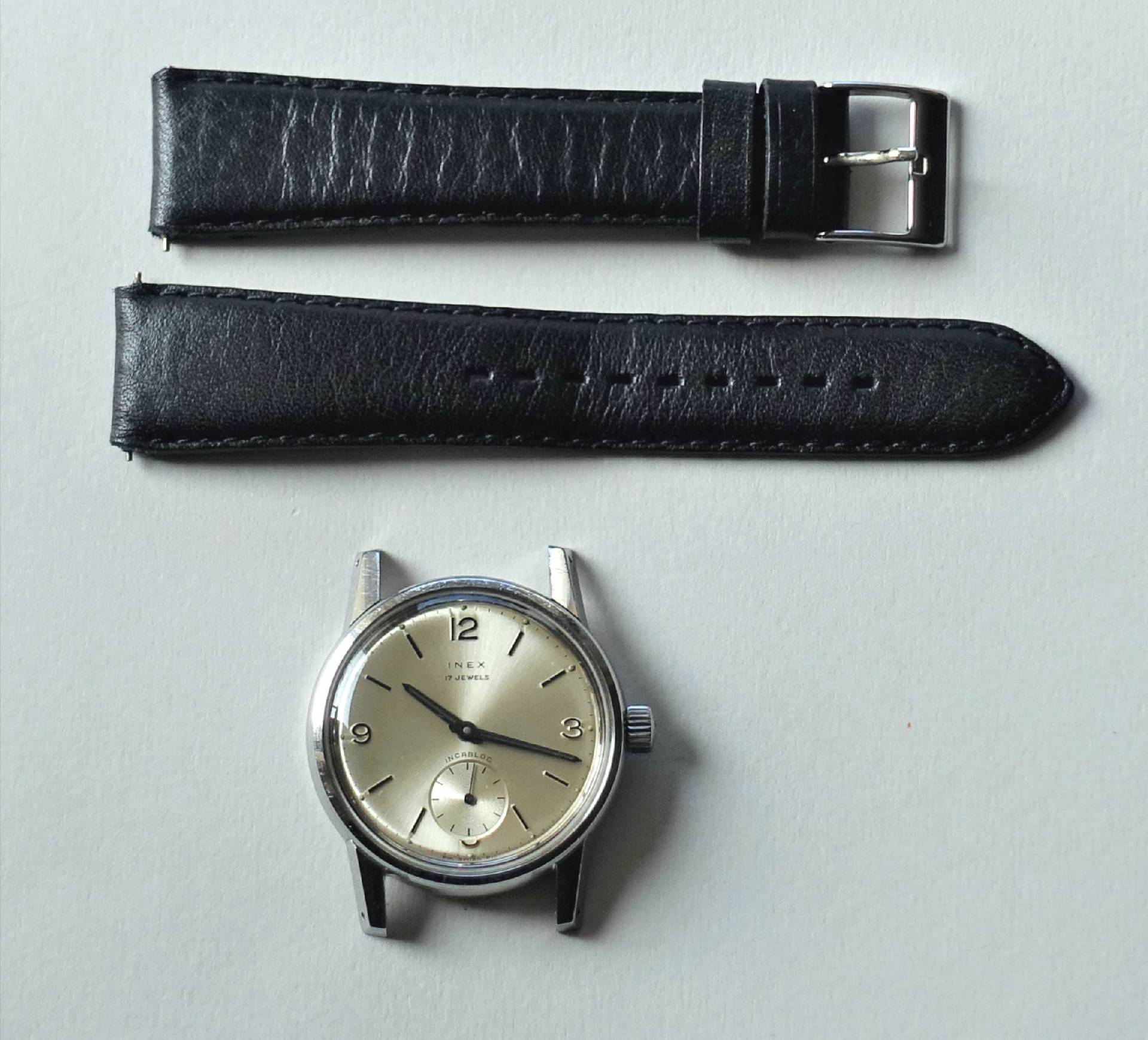 Detailbild einer klassischen Armbanduhr mit Zifferblatt und schwarzem Lederarmband