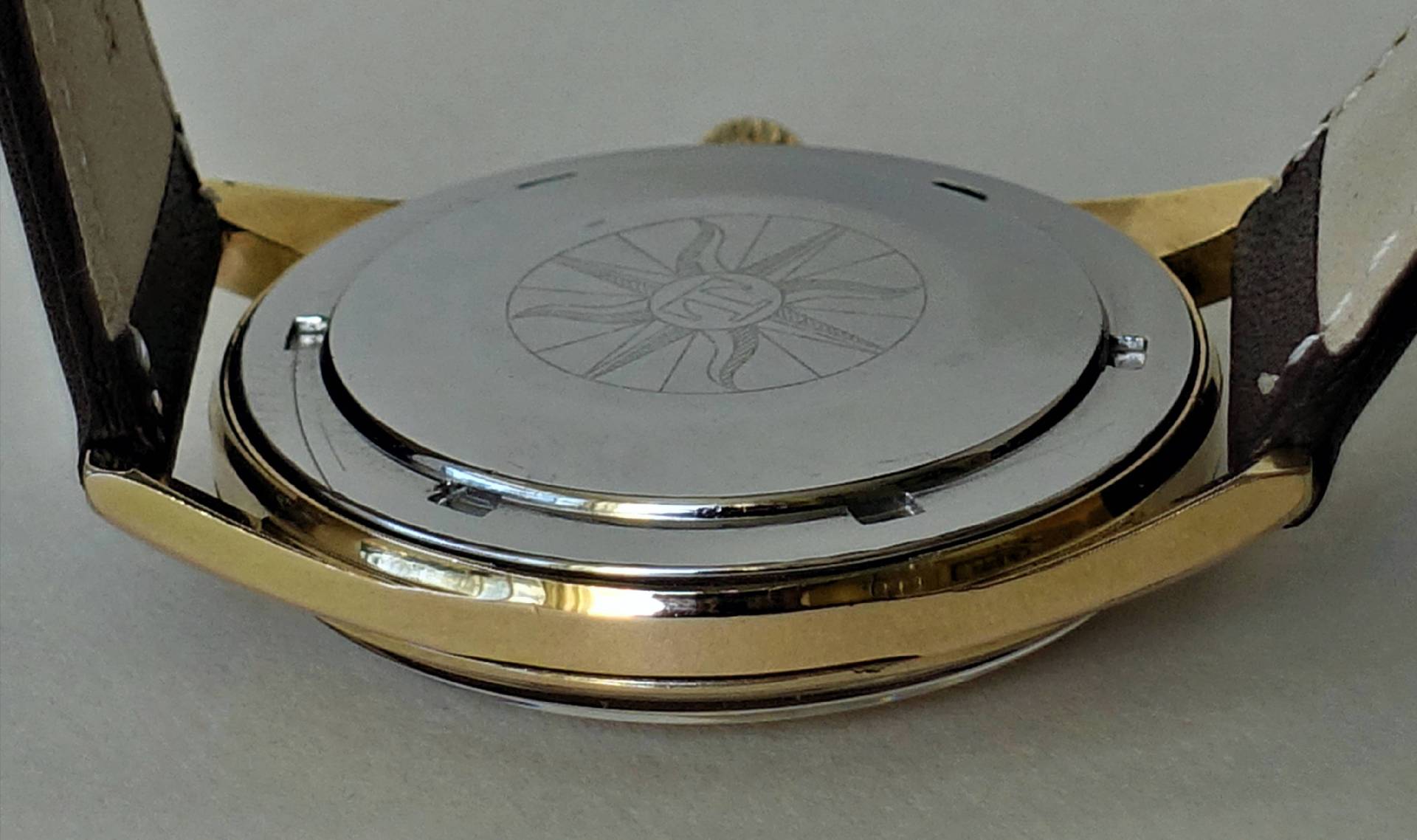 Silberfarbener Uhrenboden mit Gravur an einer Armbanduhr.