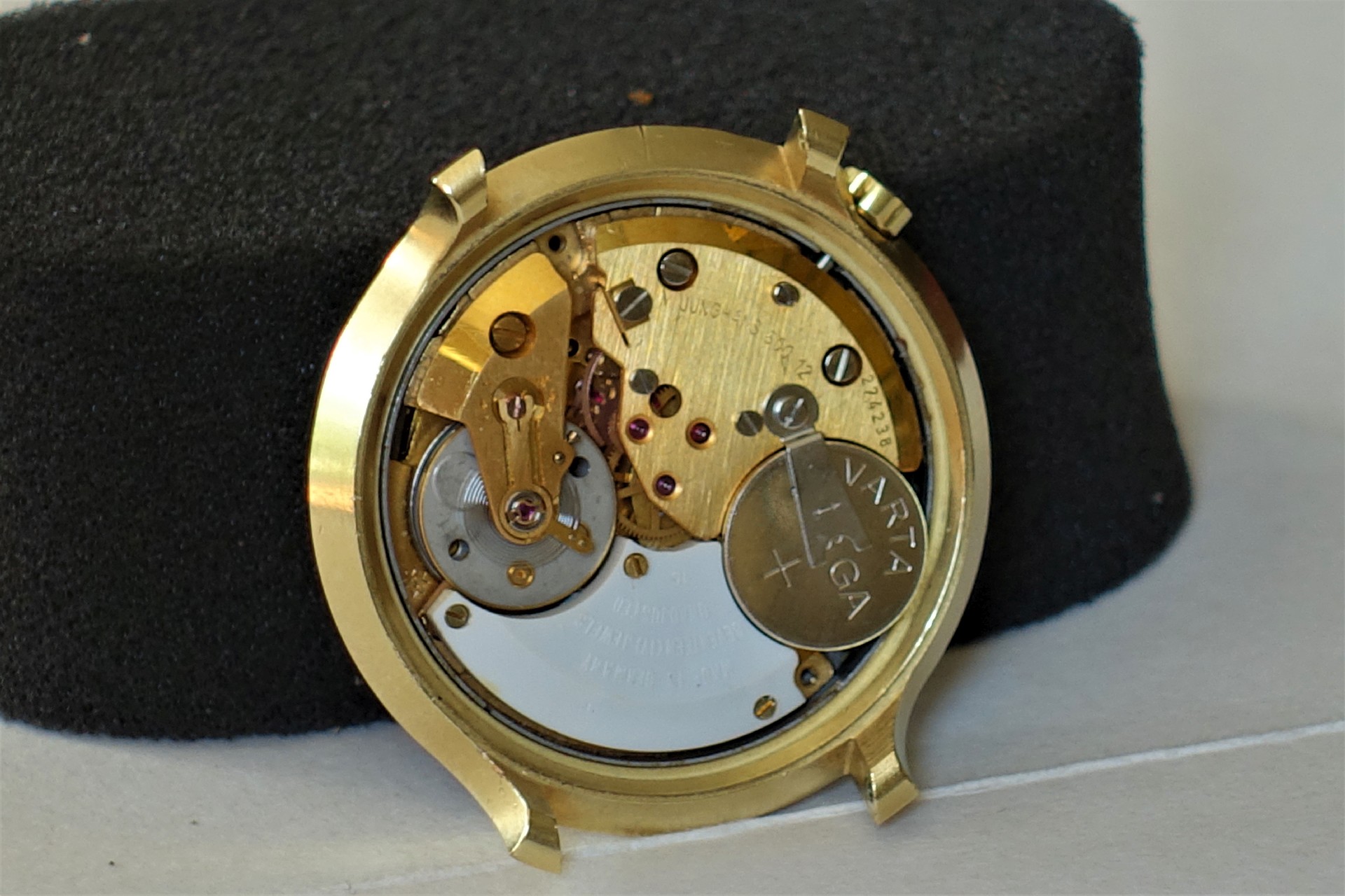 Quarzuhrwerk in goldfarbenem Gehäuse mit sichtbarer Batterie.