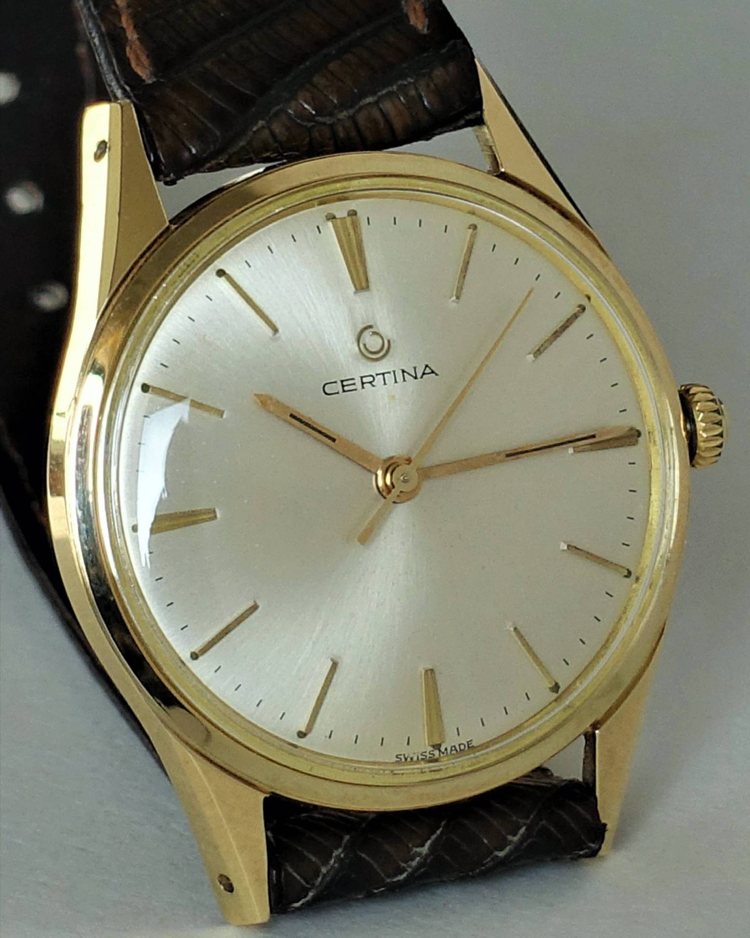 Goldfarbene Certina Armbanduhr mit hellem Zifferblatt und braunem Lederarmband.