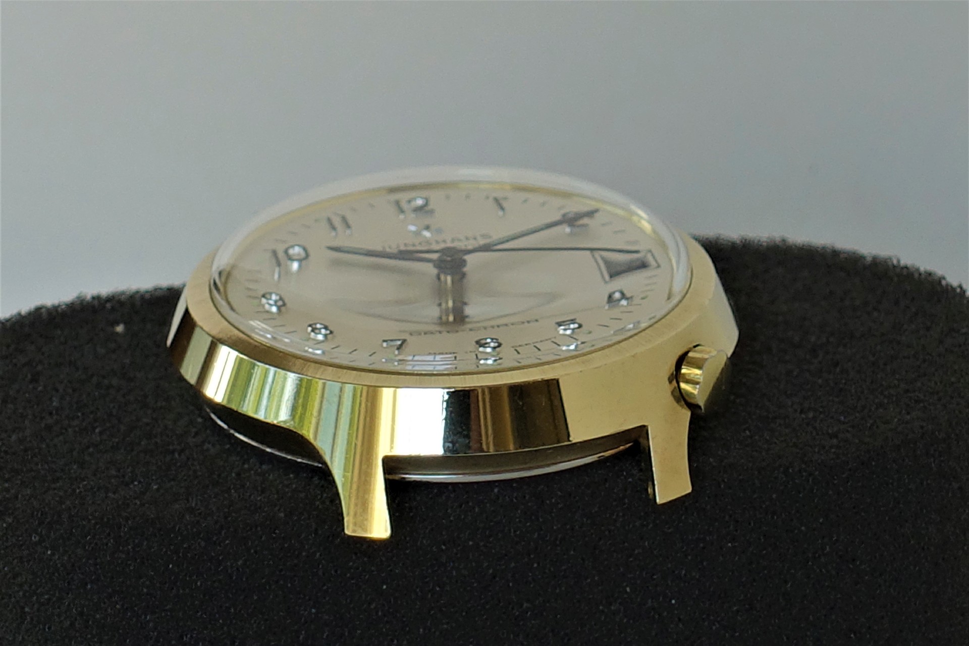 Rundes Uhrgehäuse in goldfarbener Ausführung mit Zifferblatt und Zeigern.