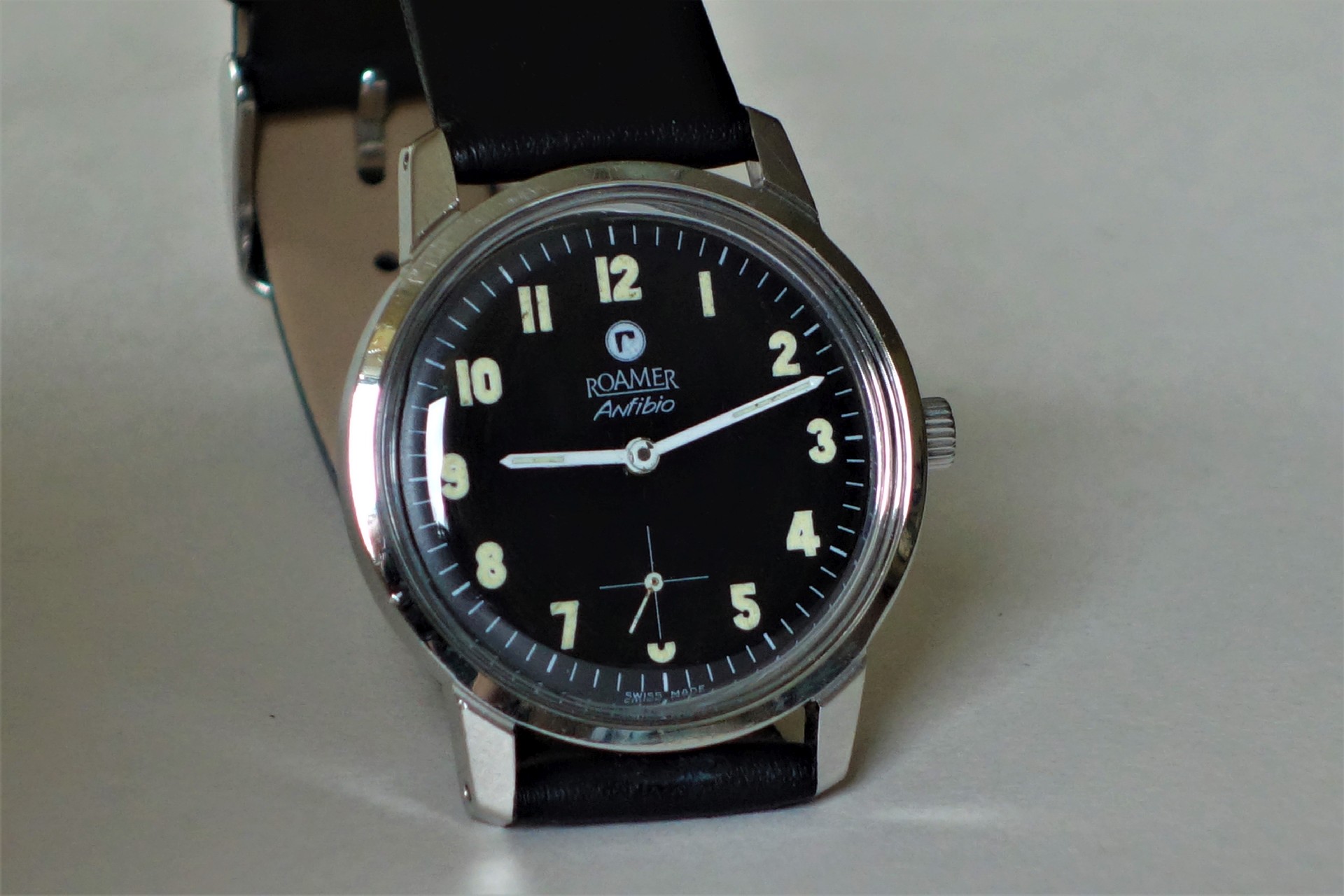 Schwarze Armbanduhr mit hellem Zifferblatt und schwarzem Armband.