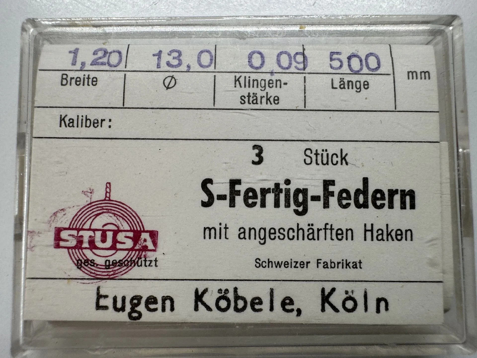 Set mit drei S-Fertig-Federn für Uhren mit angeschärften Haken in transparenter Kunststoffbox.
