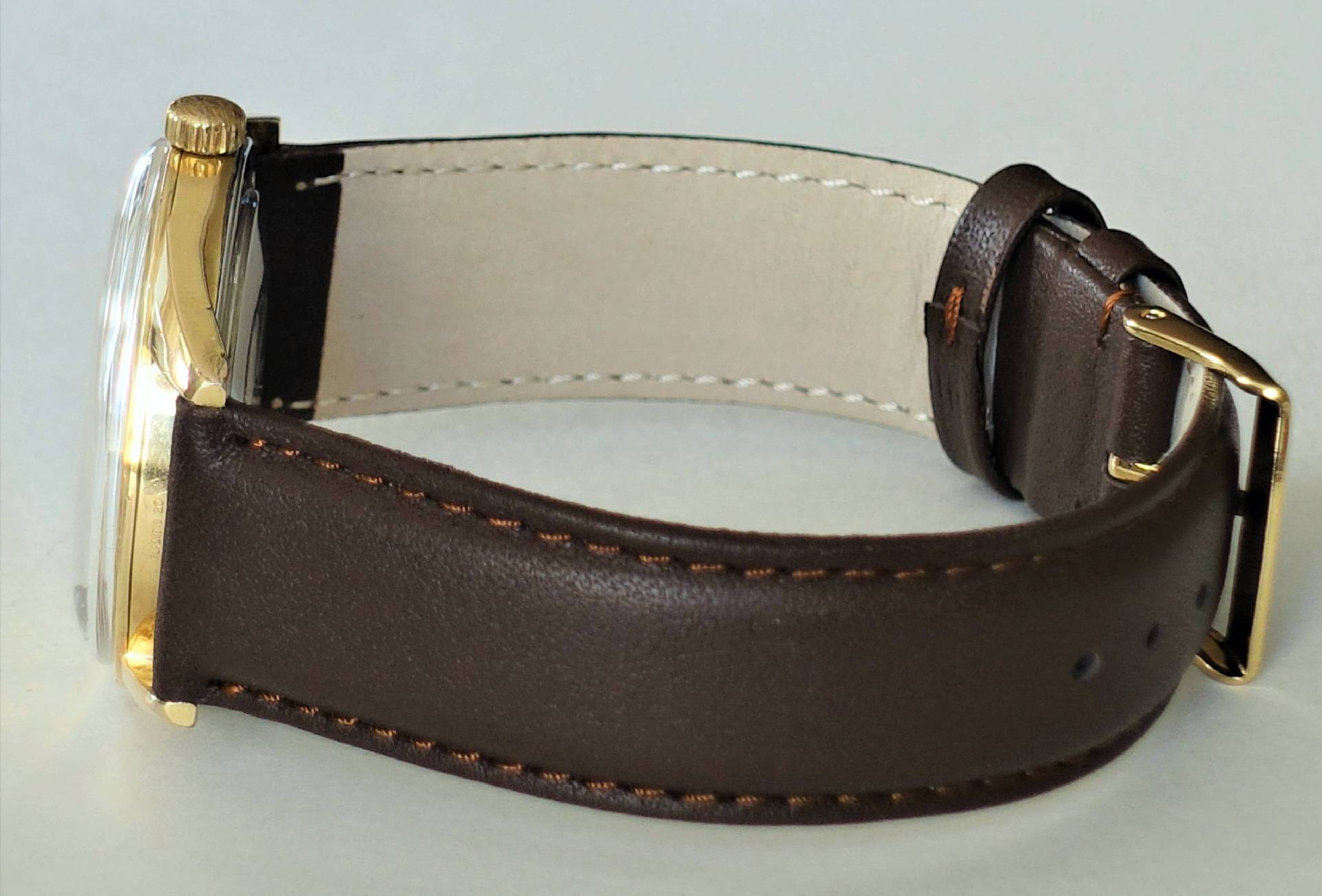 Armbanduhr mit braunem Armband und goldfarbenem Gehäuse.