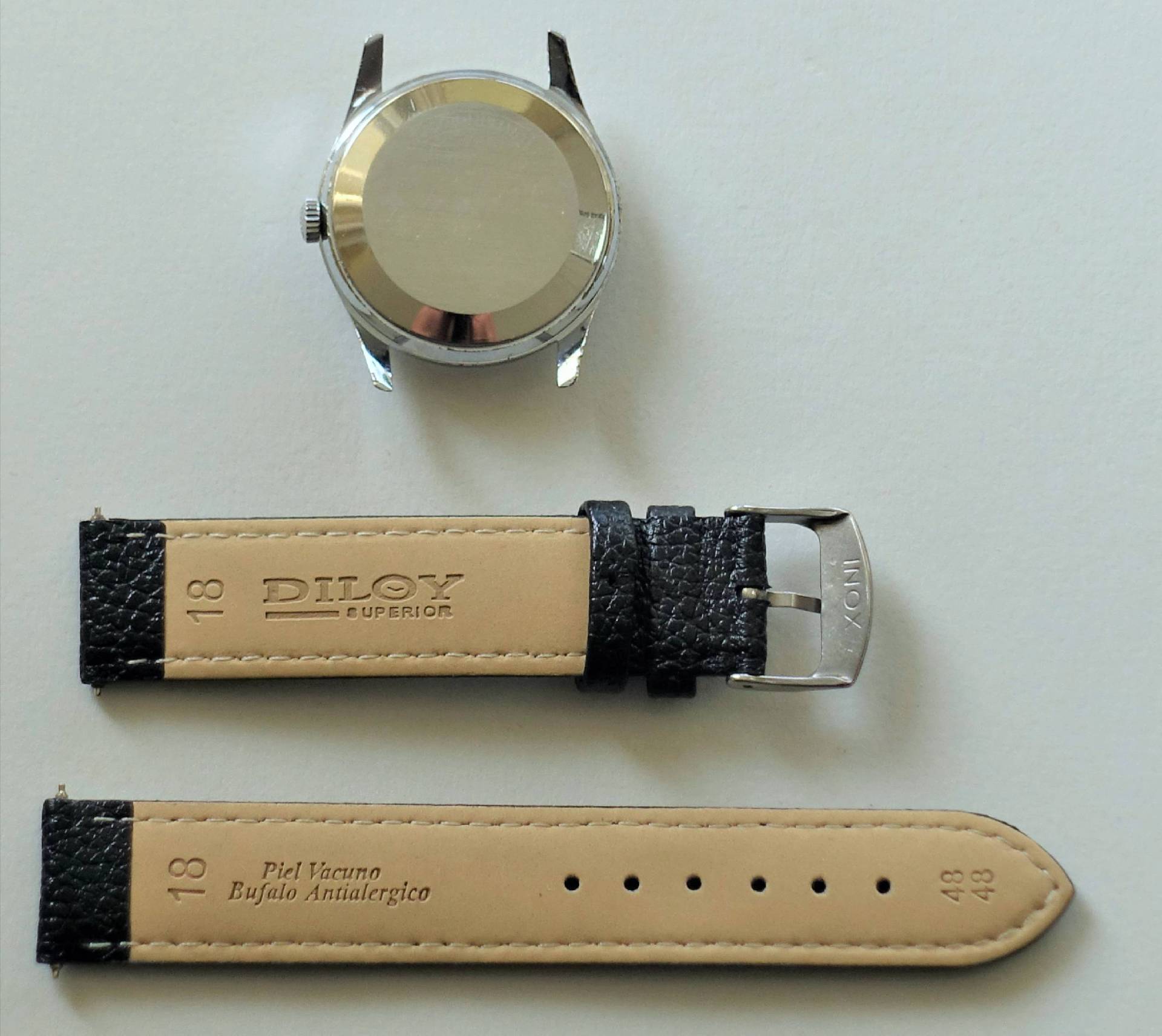 Silberfarbenes Uhrengehäuse mit schwarzem Lederarmband und Metallschließe.