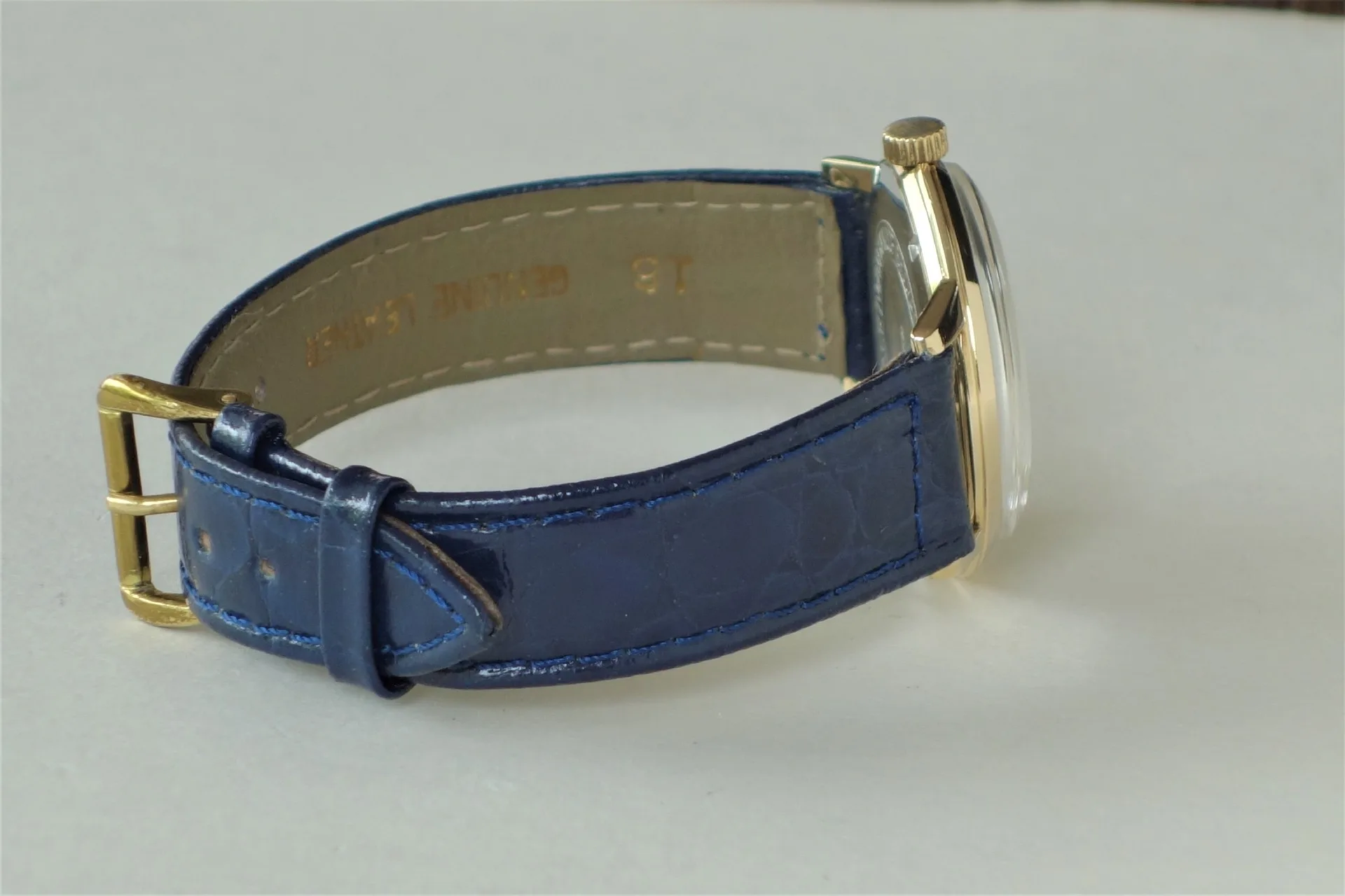 Armbanduhr mit blauem Lederarmband und goldfarbenem Gehäuse.