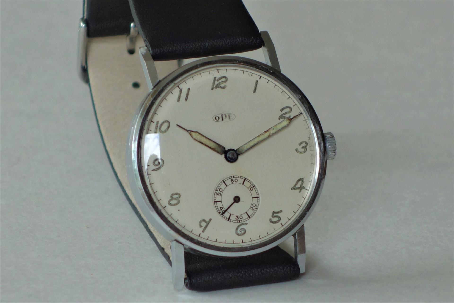 Analoge Armbanduhr mit weißem Zifferblatt und schwarzem Armband.