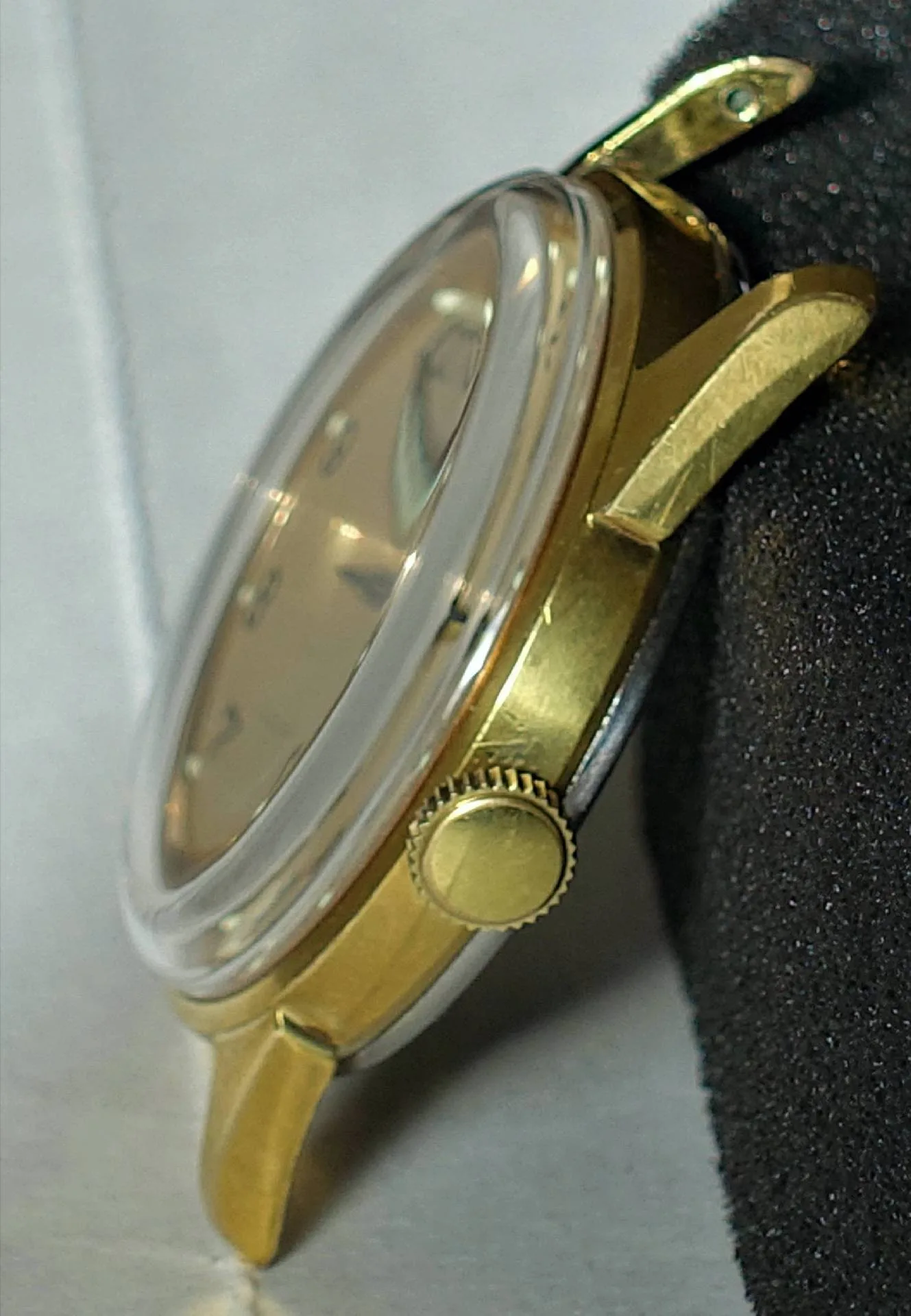 Goldfarbene Armbanduhr mit rundem Gehäuse und seitlicher Krone.